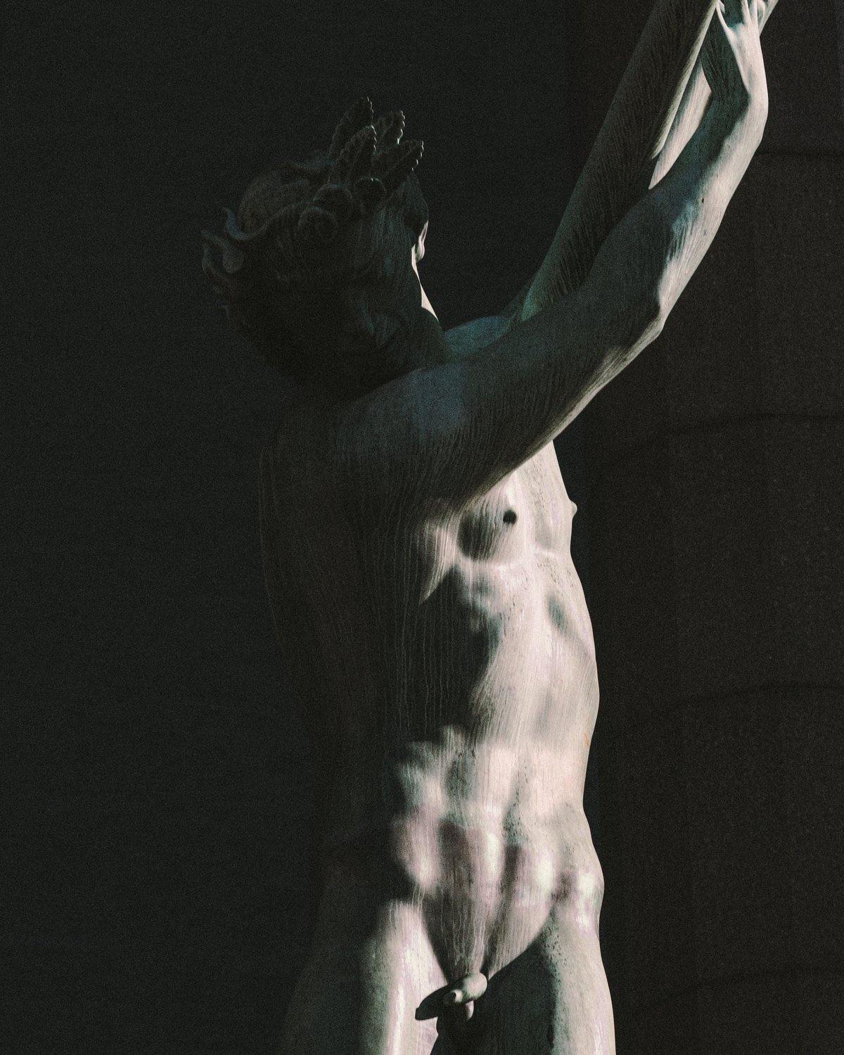 Eine Bronzeskulptur einer stehenden männlichen Figur im Schatten, vor der Fassade des Konzerthauses Stockholm.