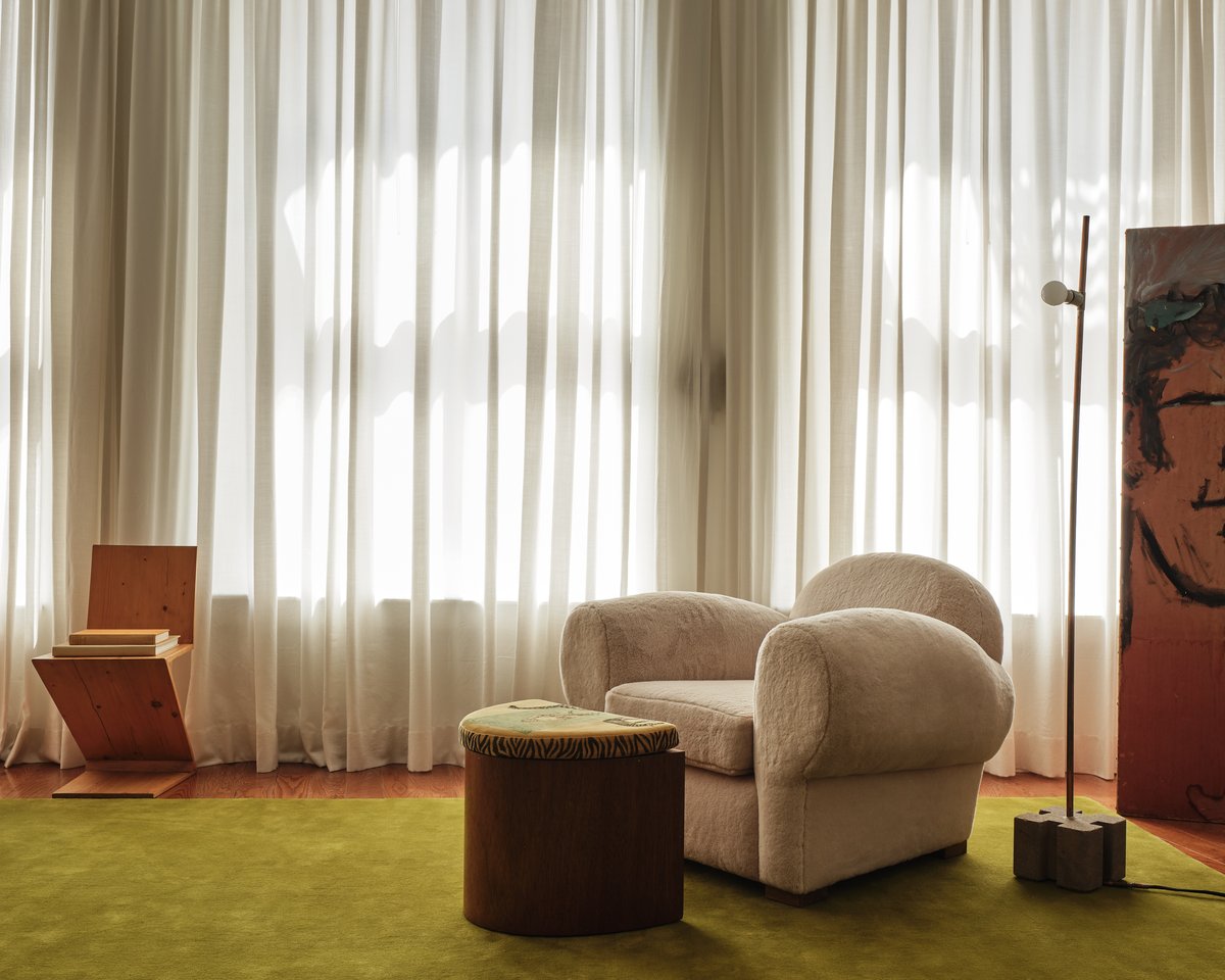 Plush wool rug Grand Milano Green displayed in a living room in front of large windows that illuminate the rug and furniture in a beautiful apartment in Soho, New York.