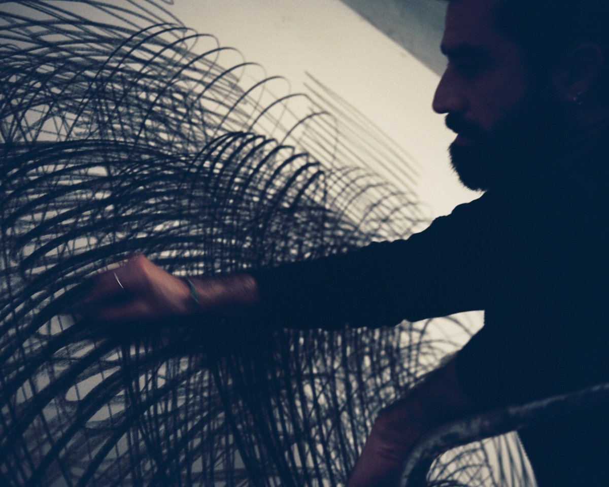 Aythamy Armas zeichnet mit Kohle auf eine leere Leinwand.