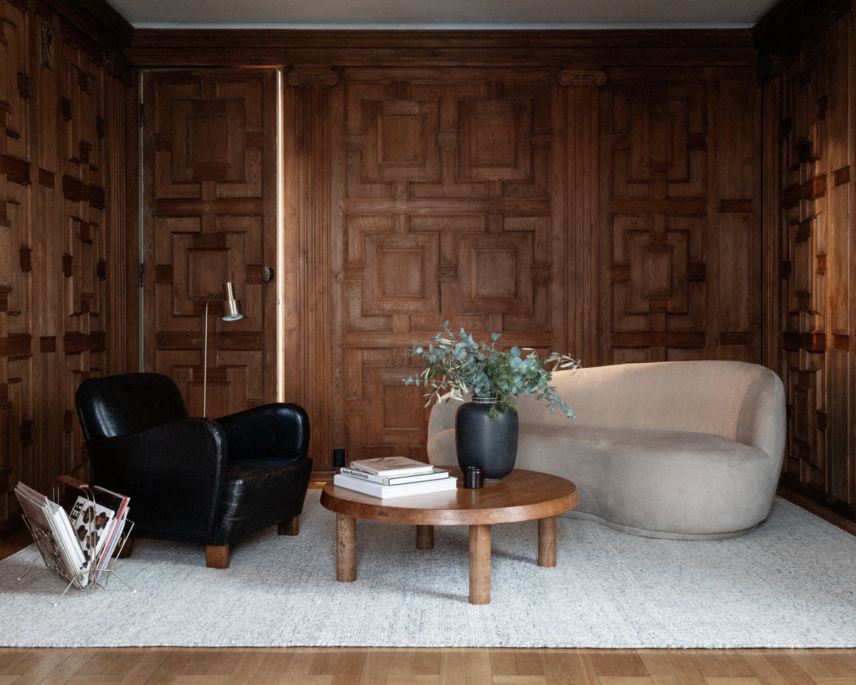 Bouclé Silver rug pictured in a living room with wooden-panelled walls and modern furniture.