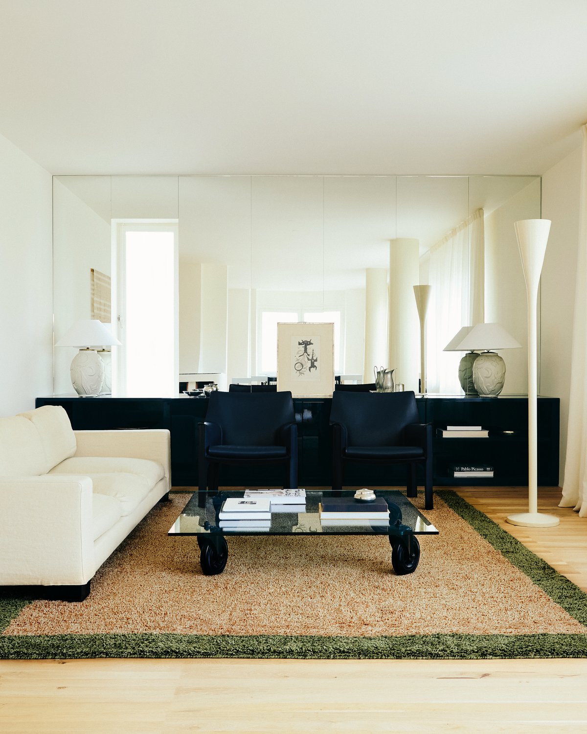 Shaggy wool rug Ryya in Beige pictured in a brightly lit living room with black interior design details and a white sofa.