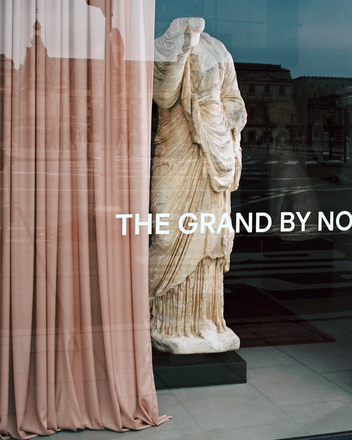 Le rideau Grand en Old Rose, drapé près d’une statue en marbre avec vue sur une fenêtre à la Galerie Chenel à Paris.