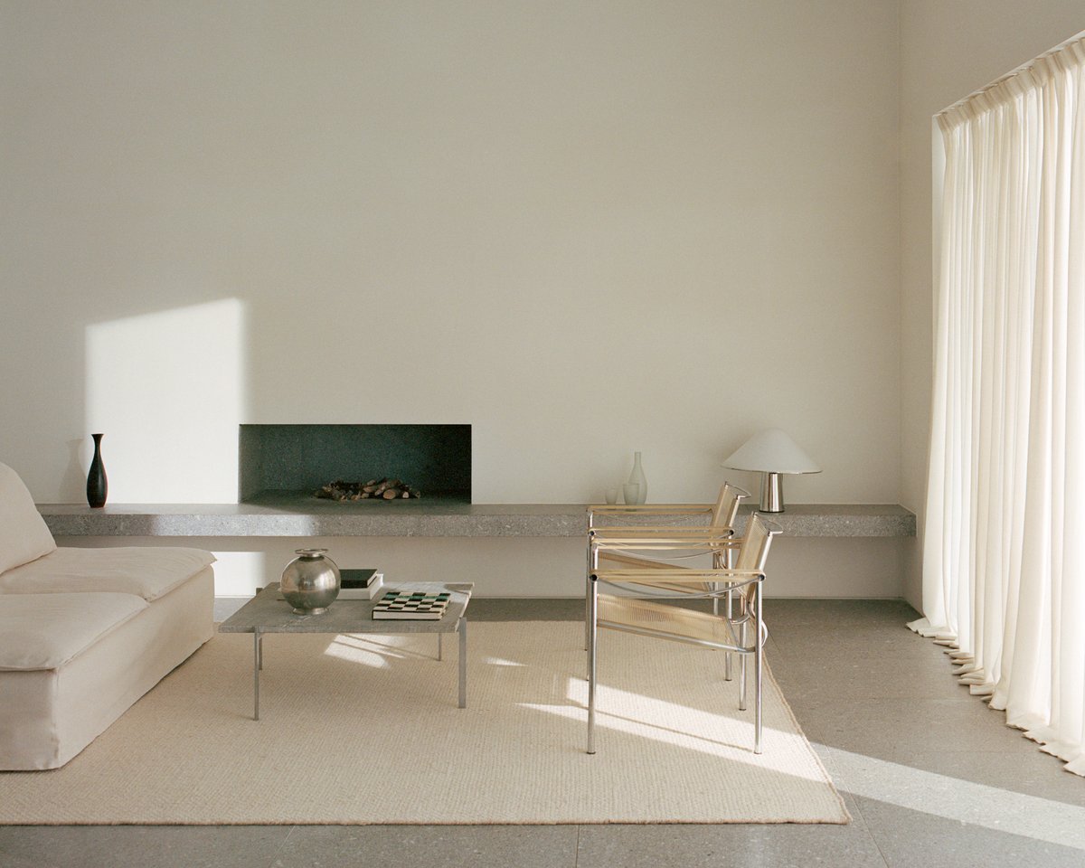 Tapis en laine tissé à plat Zero Basket Sand Mix, photographié dans un salon moderne avec des meubles de couleur claire et des éléments en béton, à Falsterbo, Suède.