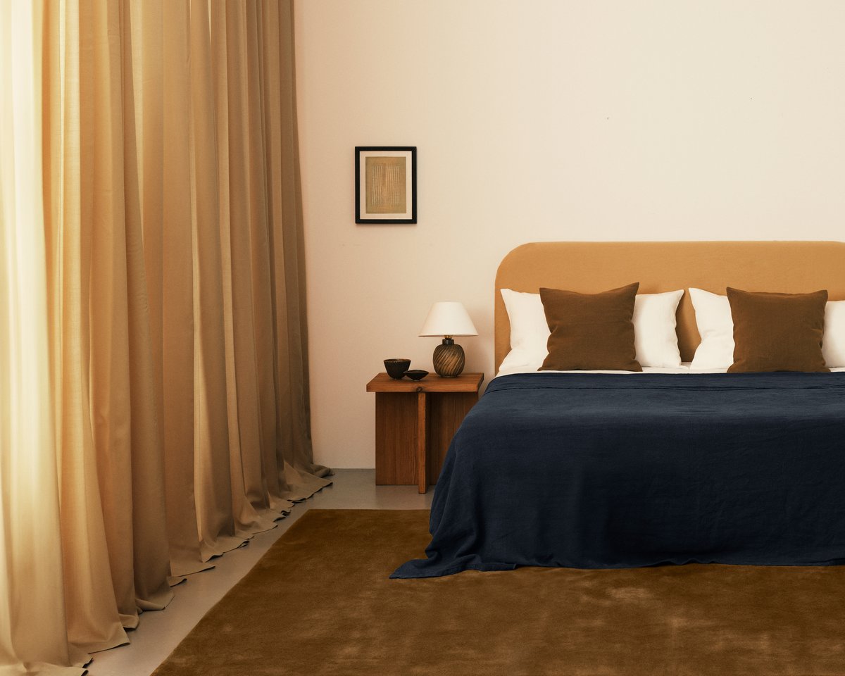 Die Vorhänge Grand Leo, abgebildet neben einem weichen Bett in einem Schlafzimmer mit orangefarbenen und blauen Einrichtungselementen.