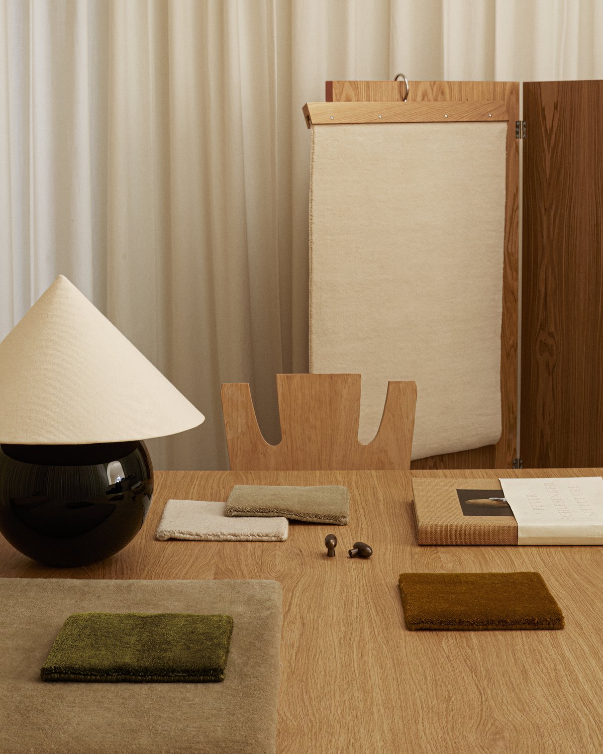 Plush wool rug Grand samples in different colors pictured on a wooden table in a modern office space.