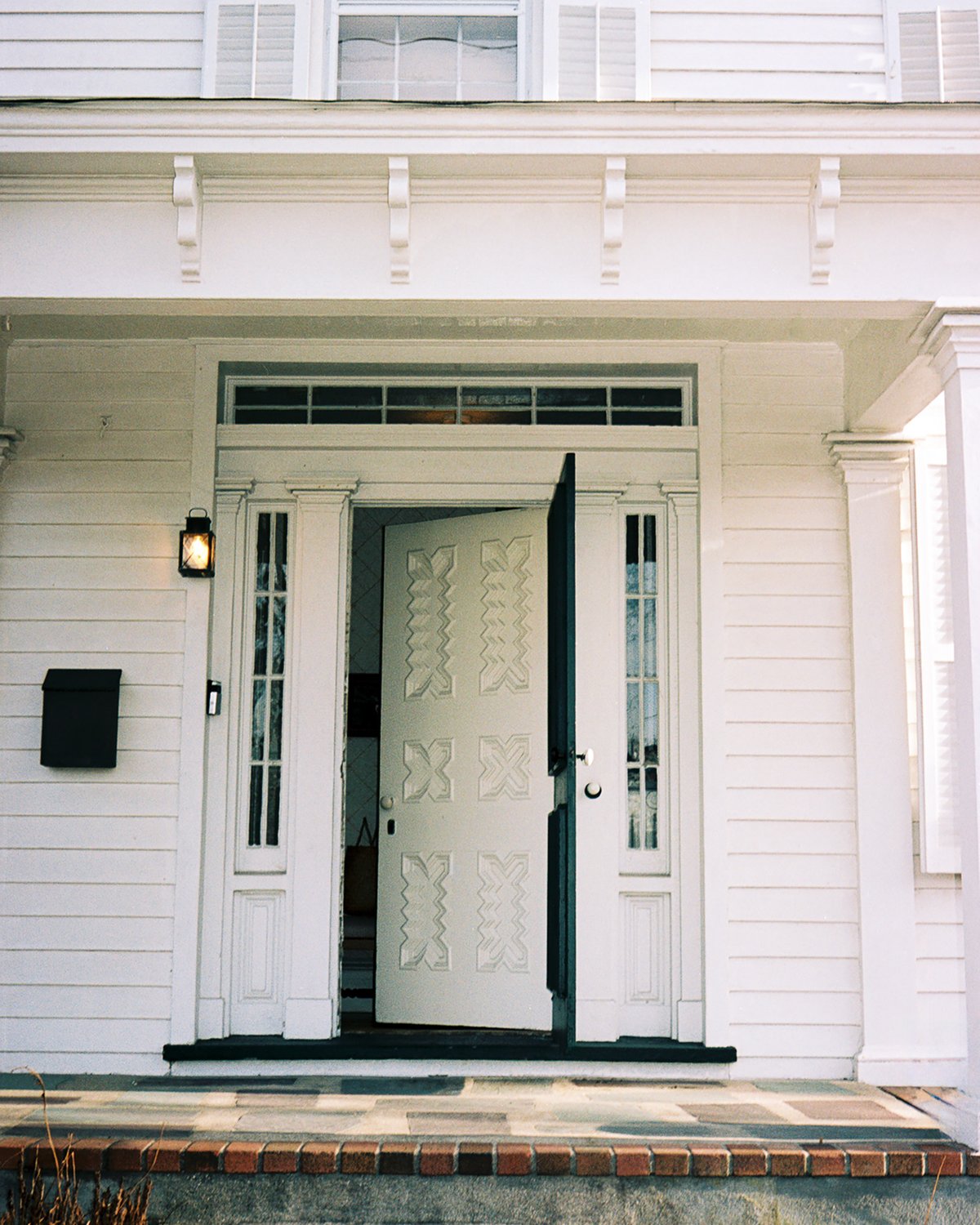 An image of a door opening to a lovely two-story white house in Bellport, USA