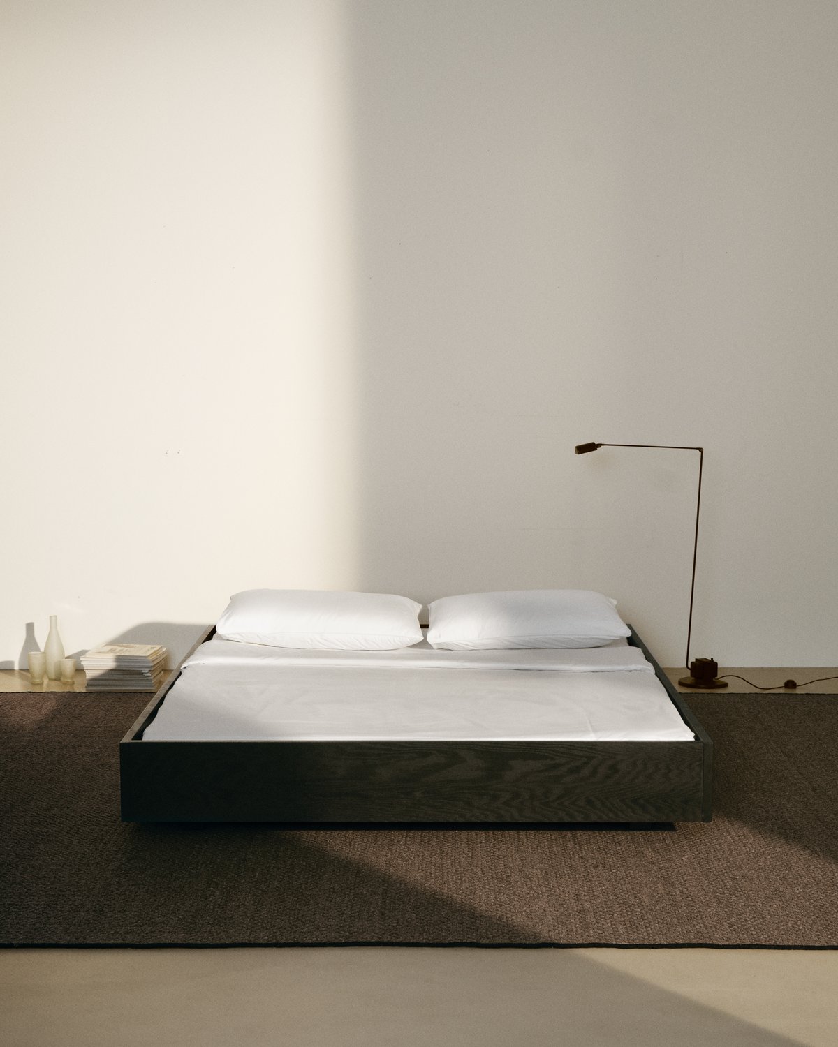 Tapis en laine tissé à plat Zero Basket en Brown, photographié avec un lit bas moderne doté d’un cadre en bois noir.