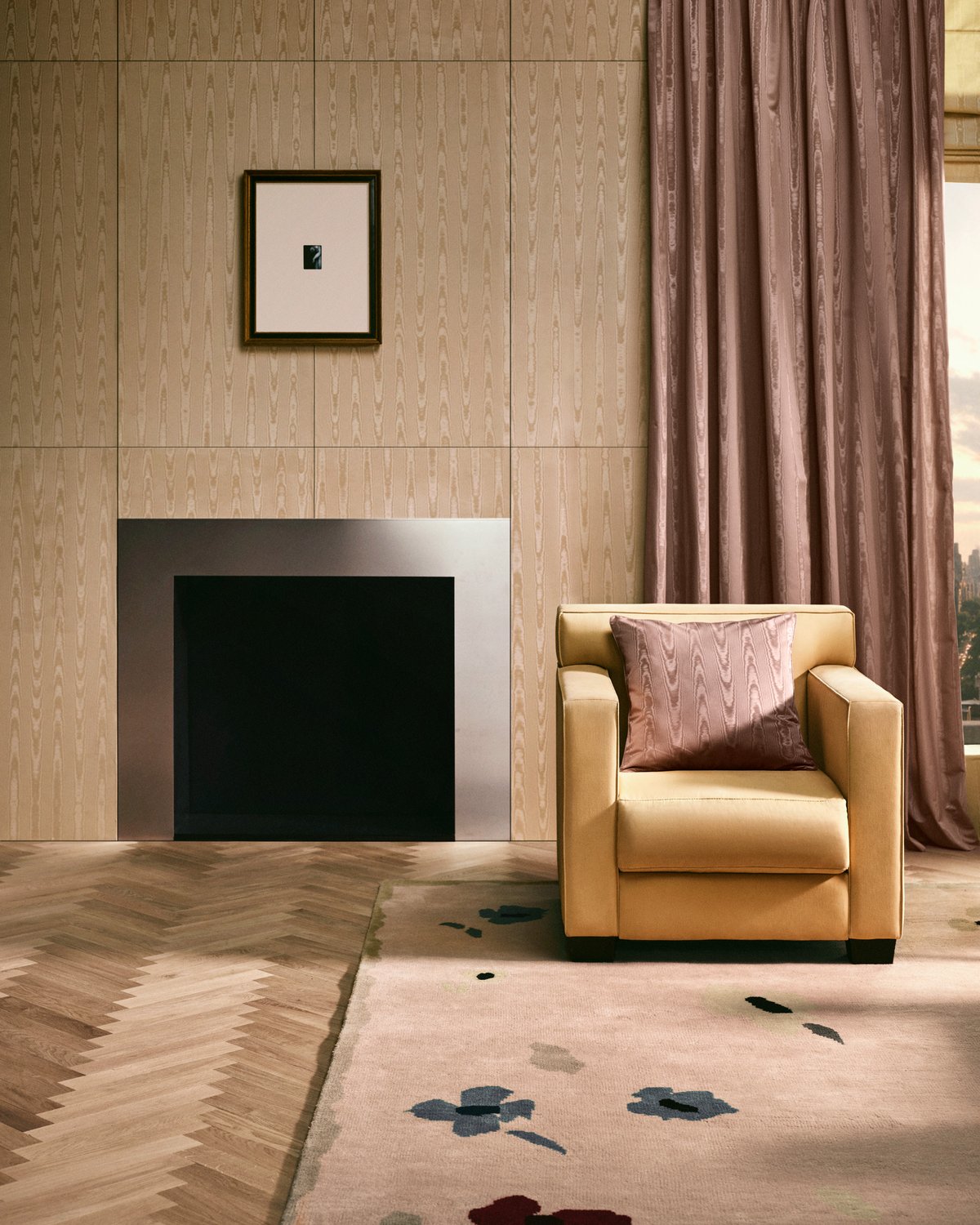 Belmont in Old Rose, a rug with scattered flowers, beneath a yellow armchair beside a steel fireplace.
