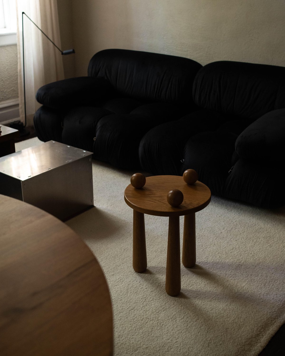 Photograph of Jessie Andrew's living room with neutral colored furniture including a large black sofa and the Merino rug.