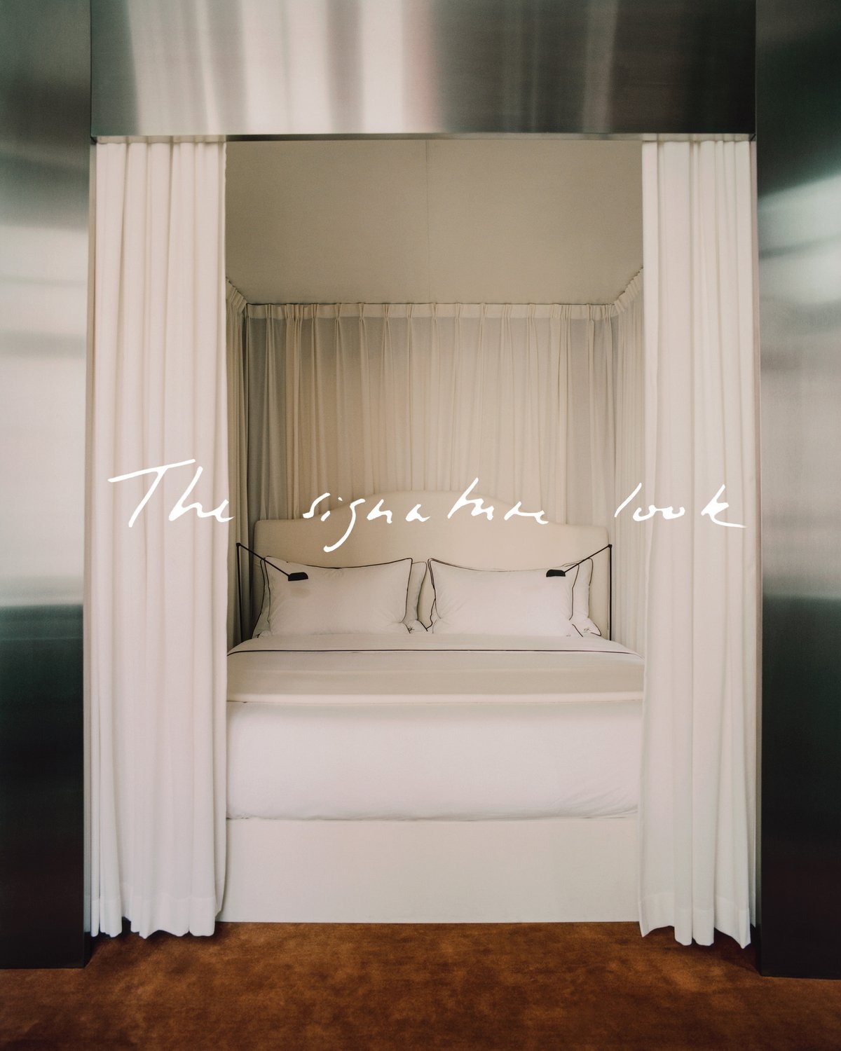 The Grand curtain in Perfect White styled around a bed, showing a soft white fabric with a smooth woven texture and full-length vertical folds framing Crisp White bedding and the Grand rug in Pecan beneath.