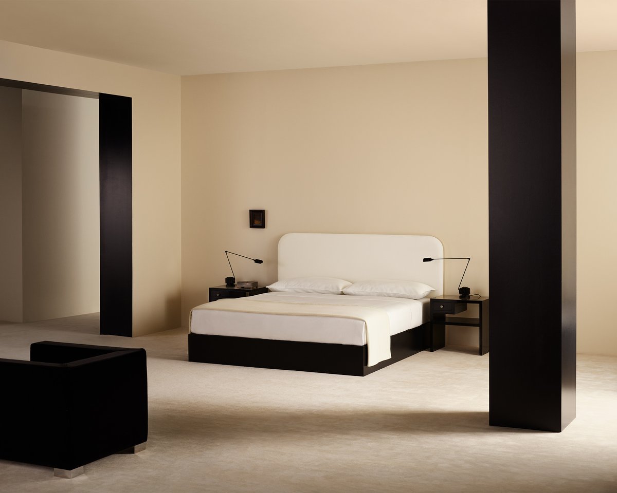 Minimalist bedroom with clean lines, soft cream walls, and white bedding from Nordic Knots Bedding & Decor Collection, styled with black accent furniture for a modern and serene atmosphere.