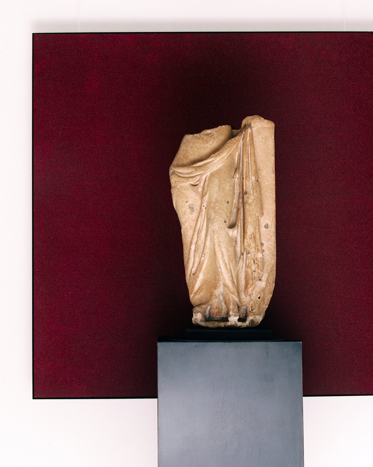 Une peinture du tapis Grand en Deep Wine accrochée au mur derrière une statue à la Galerie Chenel à Paris.