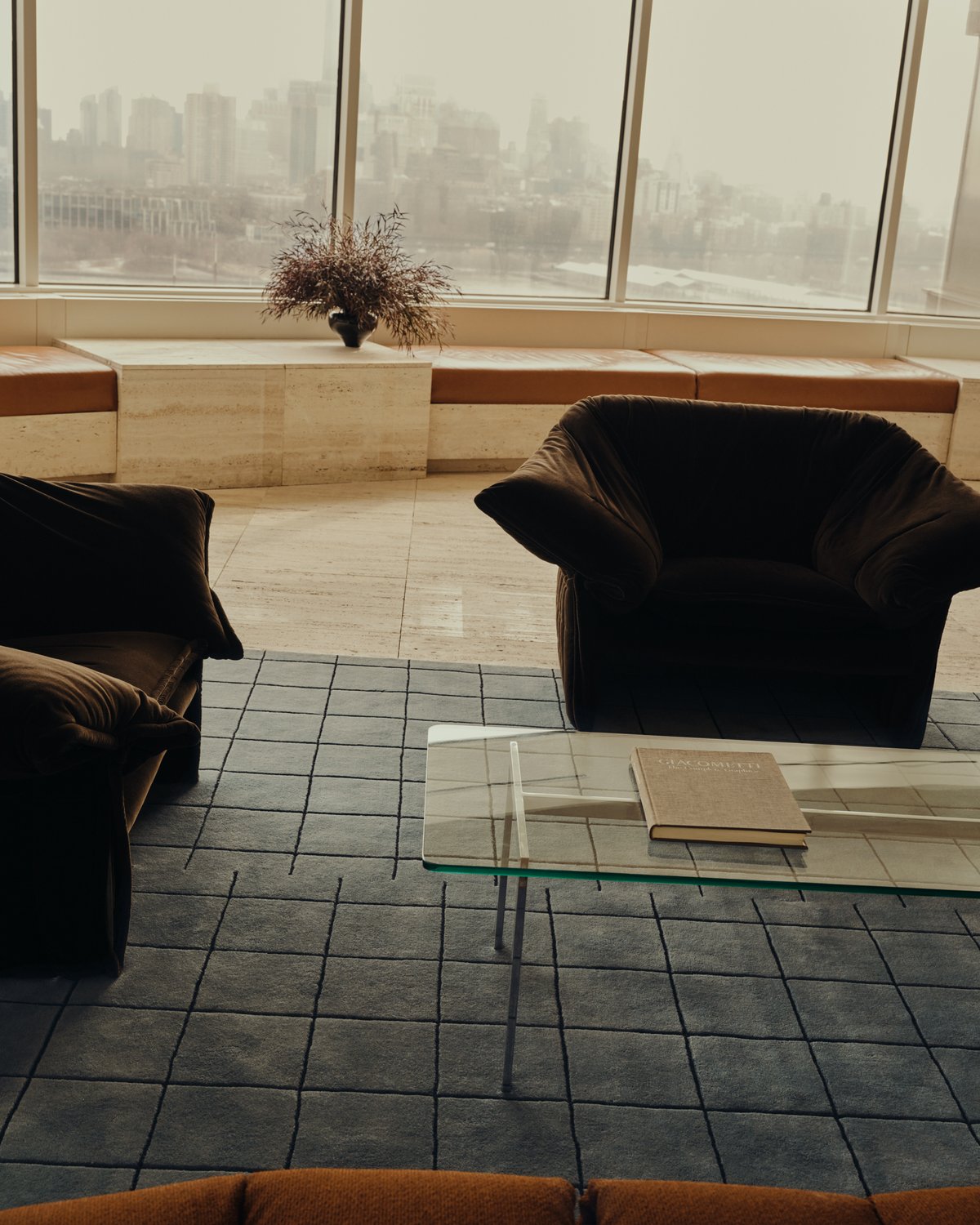 Tapis Grid en Faded Blue/Black sur un sol en marbre, présenté avec deux fauteuils bruns dans un gratte-ciel à New York, États-Unis.