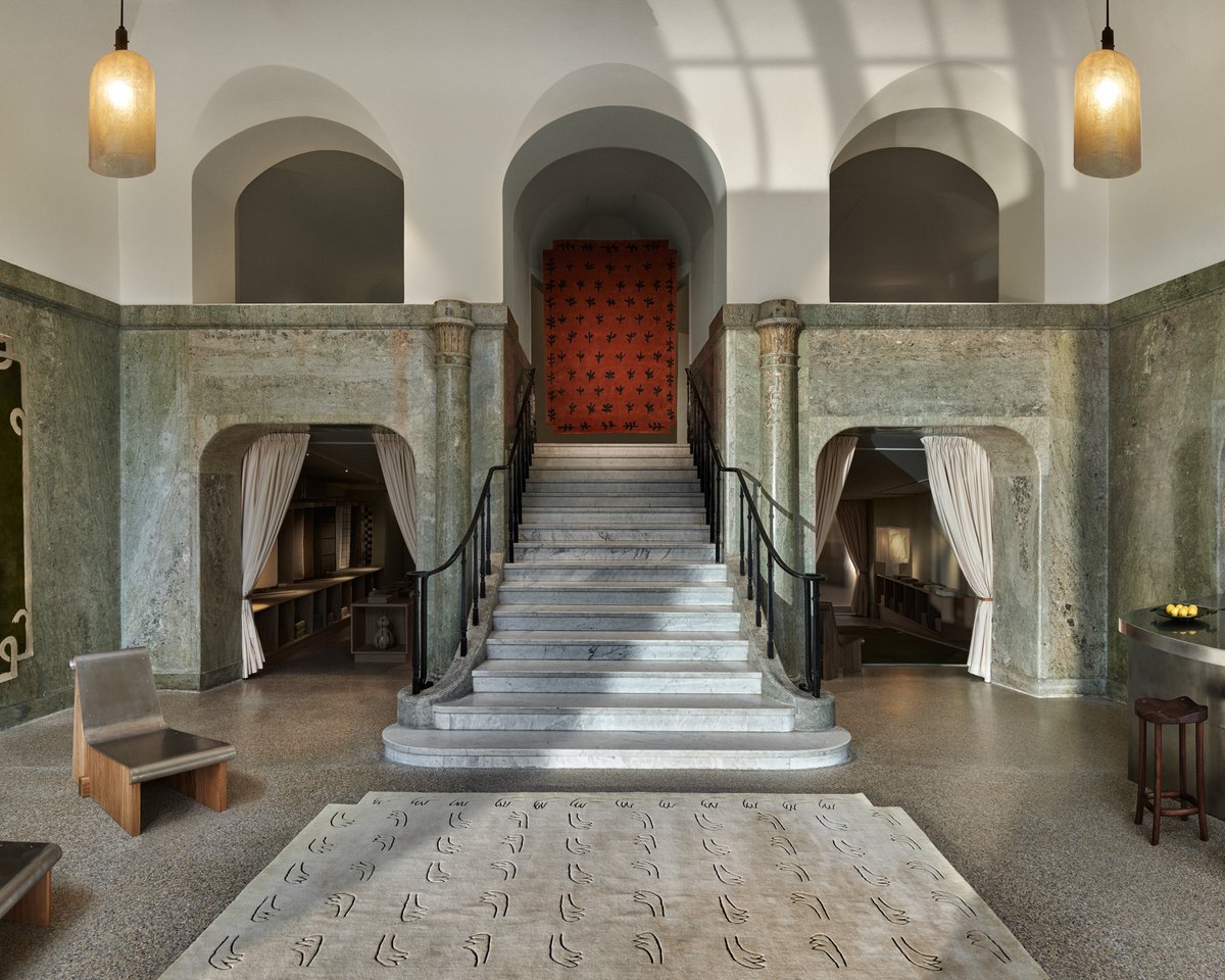 Stockholm Flagship store entrance staircase with the All Hands Beige rug in the foreground, and the Big Buds rug hanging on the second floor above the stairs.