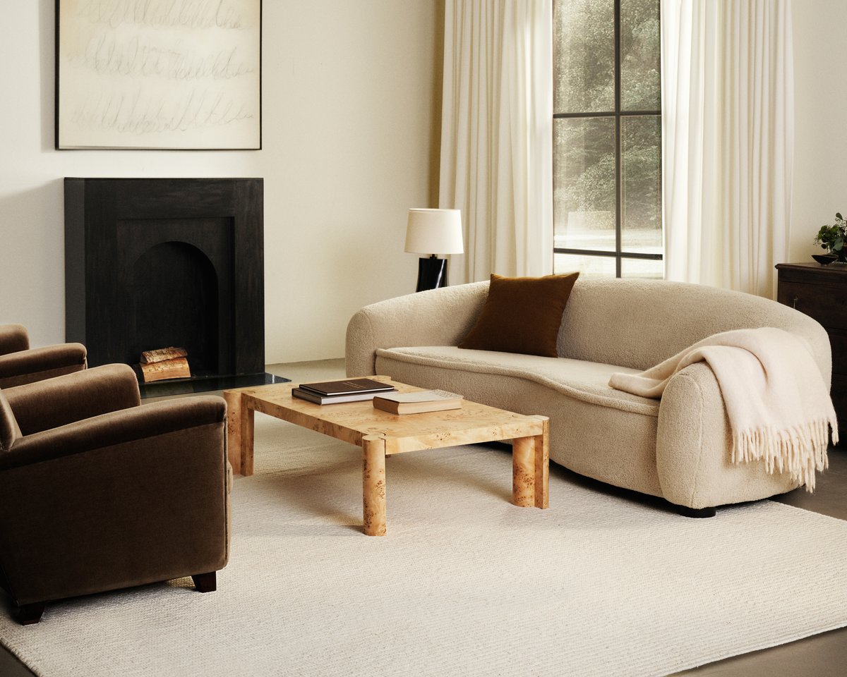 Flatweave wool rug Braid in Cream pictured in a living room with a black fireplace and white sofa.