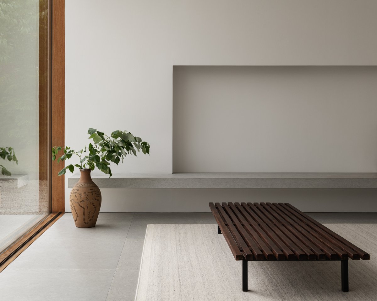 Zero Cream Mix rug pictured underneath a dark wooden bench in a white modern space.