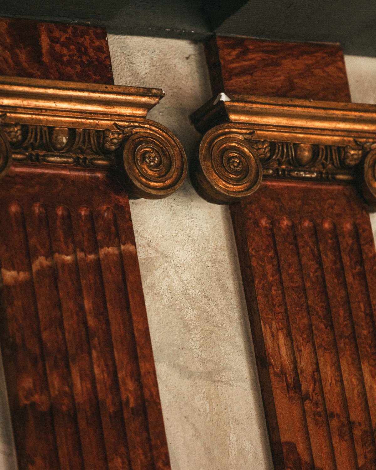 Gilded Ionic-style columns with rich wooden texture and ornate capitals, part of the interior architecture at Stockholm Concert Hall.