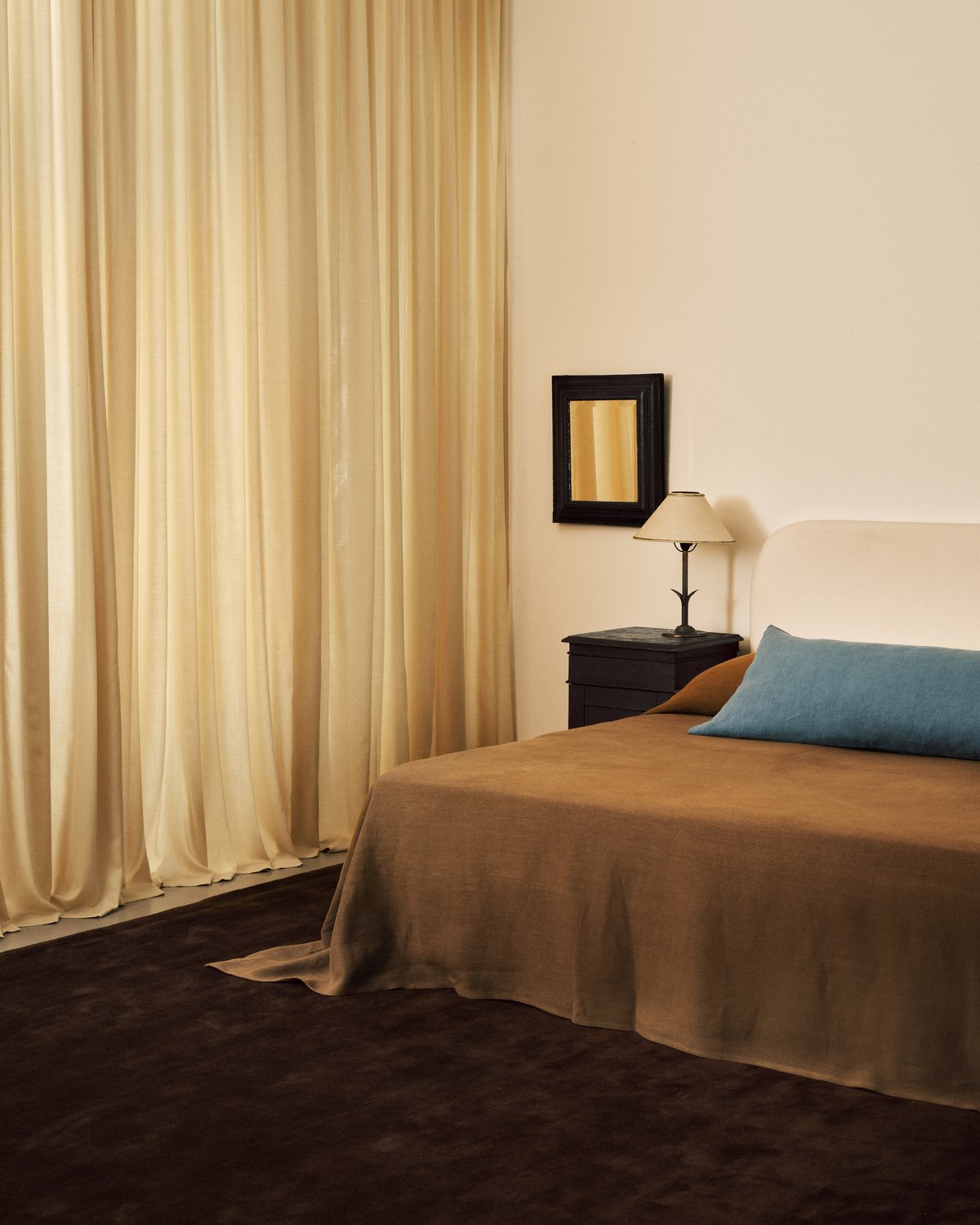 Die The Grand-Vorhänge in der Farbe Sunrise, abgebildet in einem Schlafzimmer mit braunen und orangefarbenen Designdetails und dem flauschigen Wollteppich Grand Walnut.