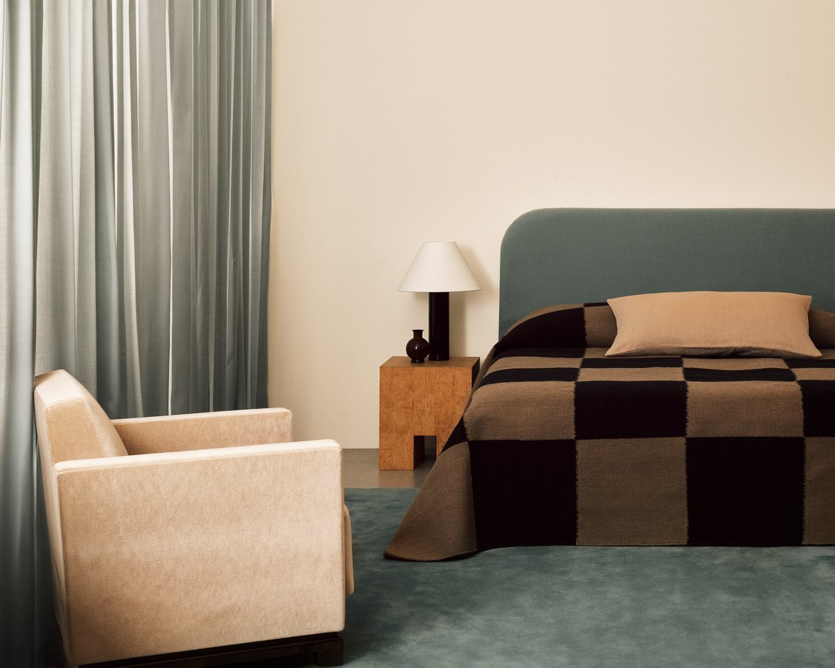 Les rideaux The Grand Pale Blue photographiés dans un salon moderne avec un mobilier assorti et le tapis tissé à plat Square Tobacco utilisé comme couvre-lit.