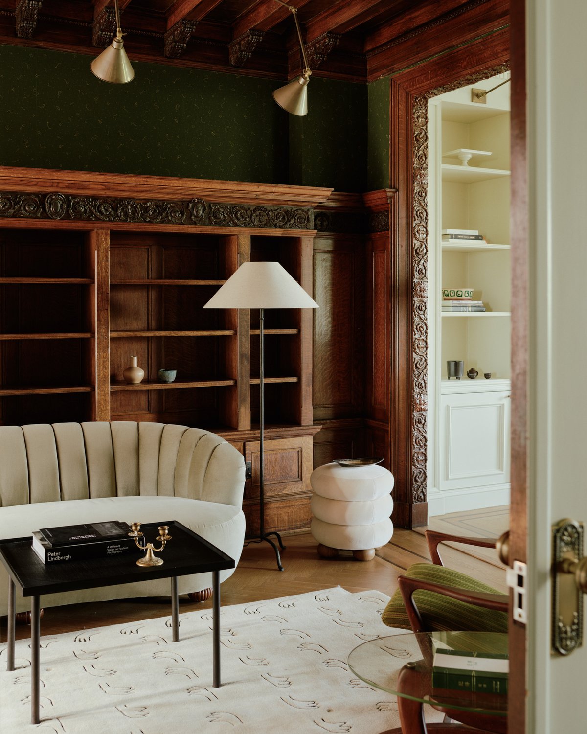 Teppich All Hands in Beige, in einem Wohnzimmer unter einem Sofa und Tisch inszeniert, zeigt einen weichen Beigeton mit glatter Oberfläche und einem dezenten, wiederholten Handmotiv.