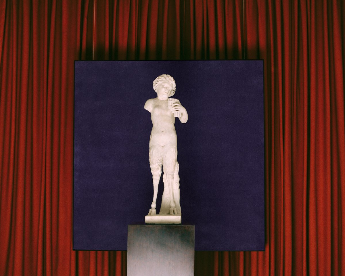 The Grand curtain in Burnt Red and a painting of the Grand rug in Lilac displayed behind a marble statue at Galerie Chenel in Paris.