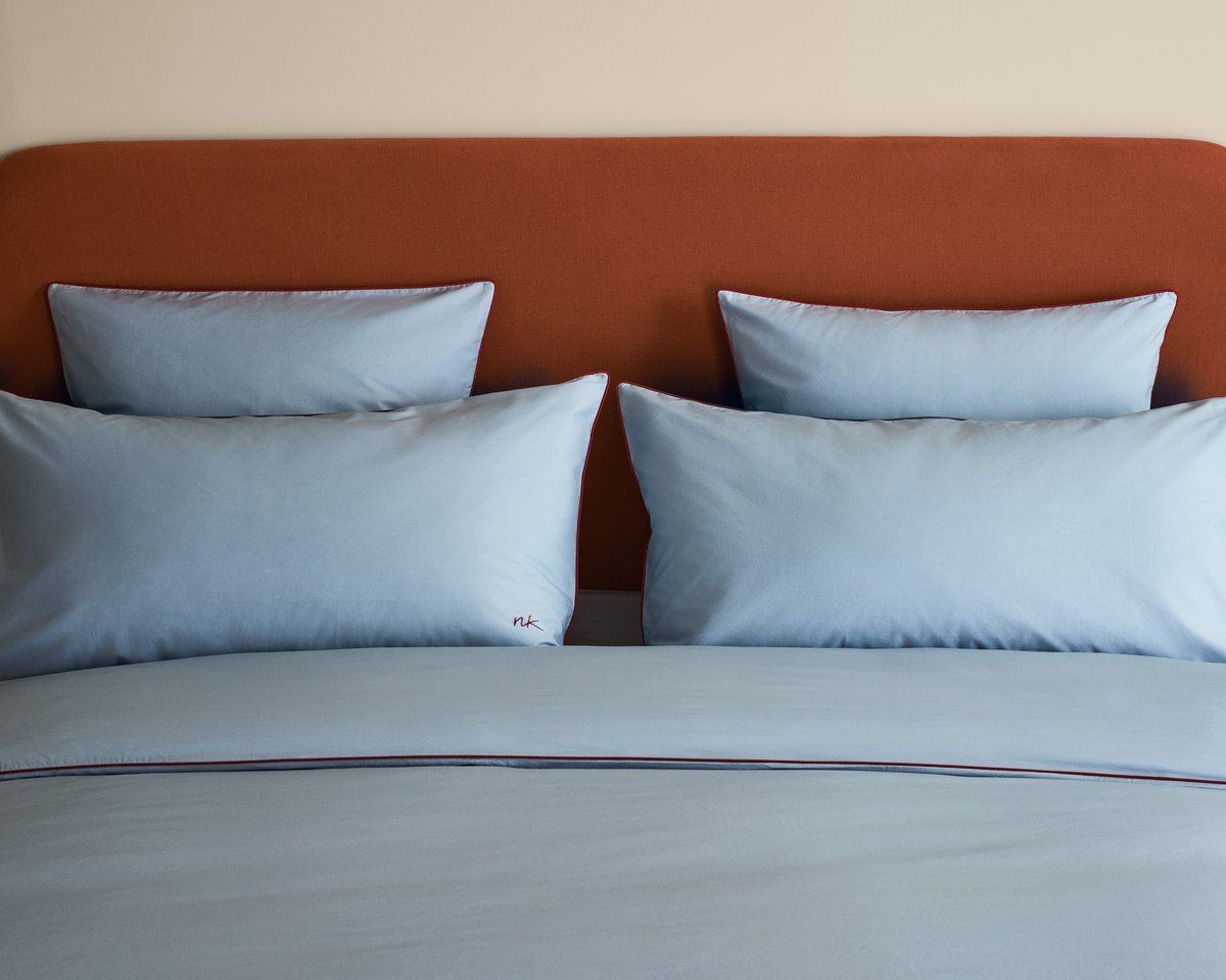 Bed styled with the Signature Headboard in Burnt Red, dressed in the Percale Bedding Collection in Shirt Blue/Red.