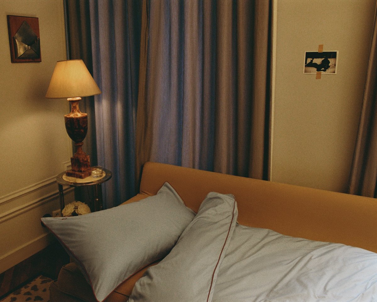 Die Percale Duvet Cover in Shirt Blue/Red ist über ein beiges Sofa in einem warm beleuchteten, gemütlichen Raum mit Marmortisch, Lampe und Vorhängen in neutralen Tönen drapiert.