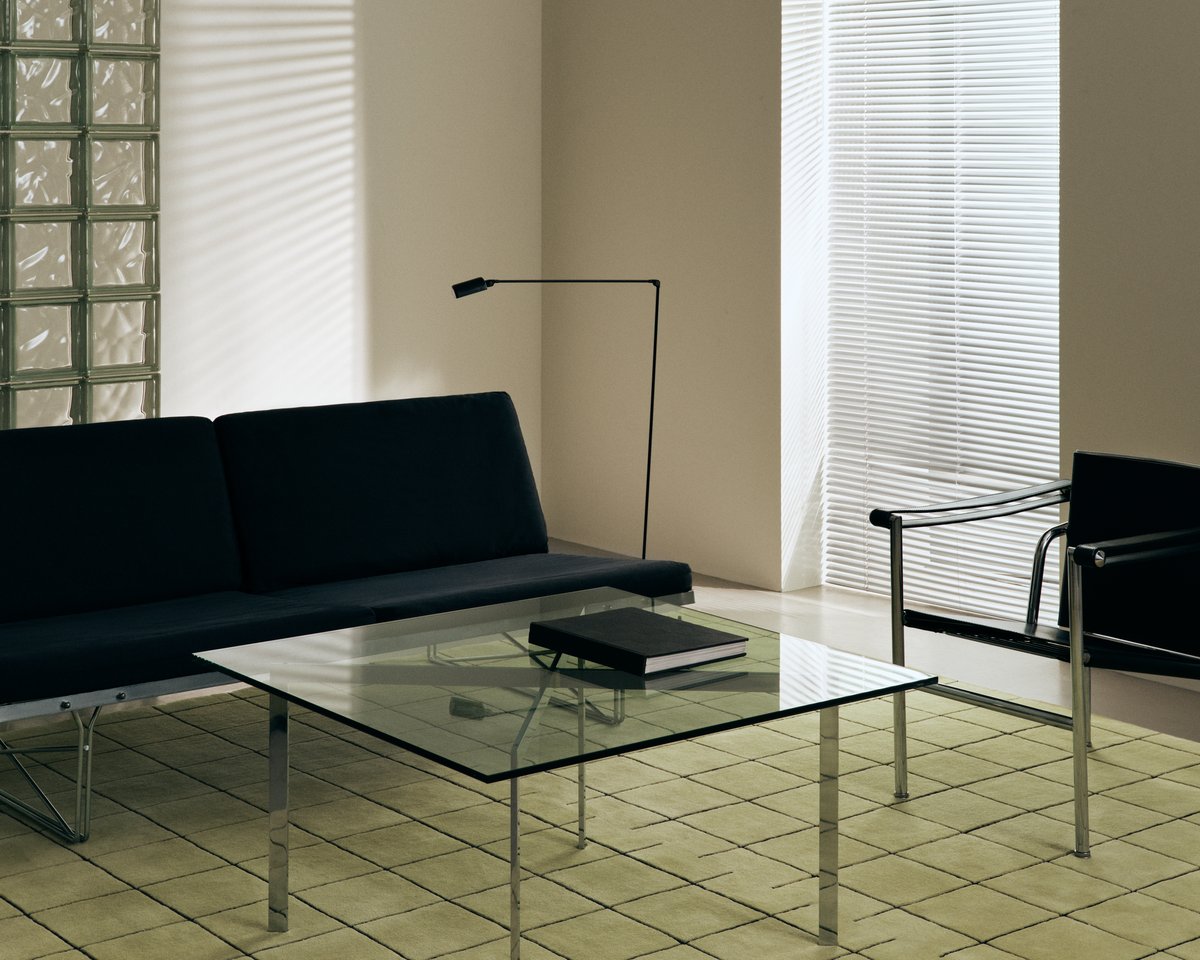 Plush wool rug Grid in Pistachio pictured with a glass coffee table and black sofa.