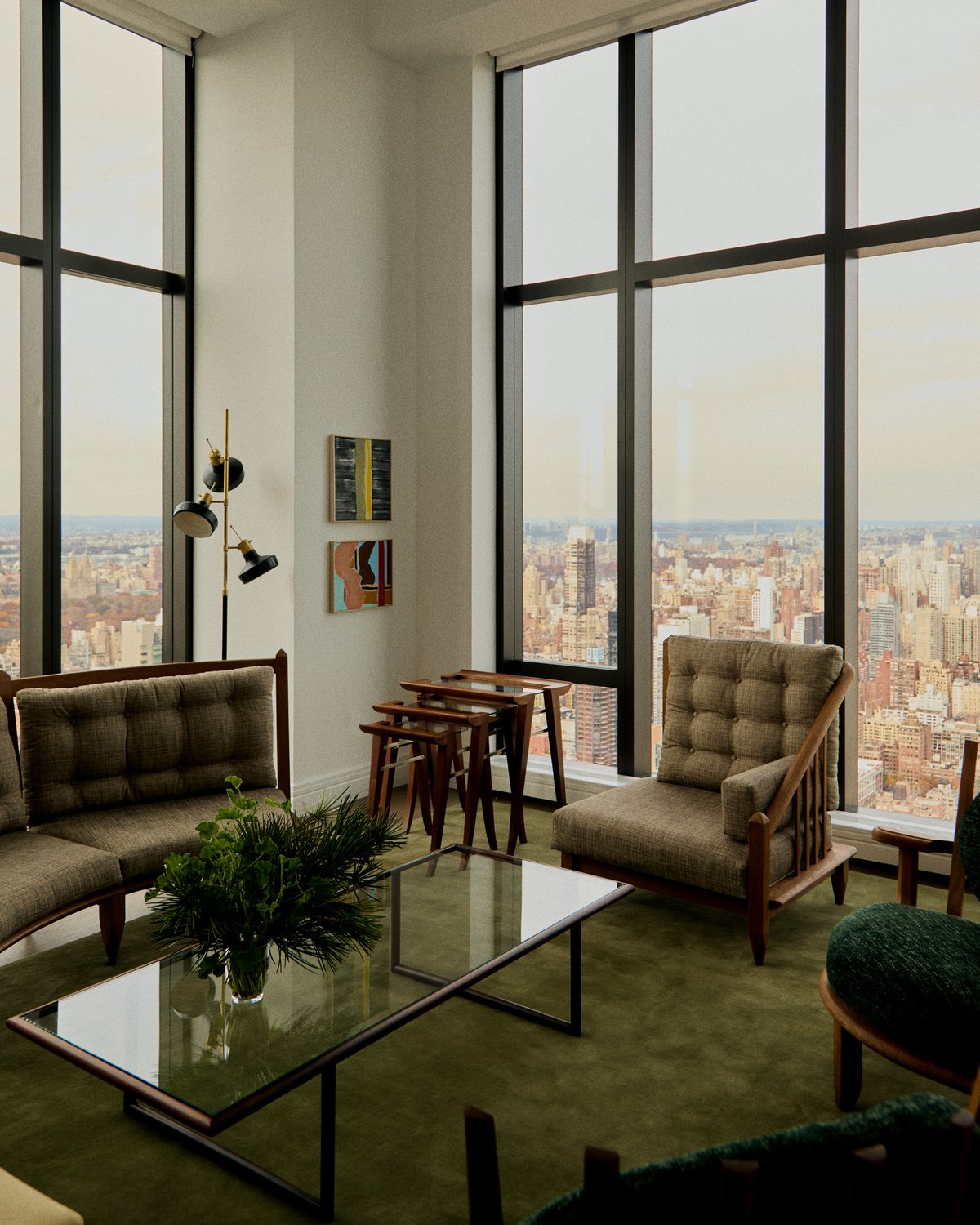 Grand in Moss, photographed in a bright living room with floor-to-ceiling windows, beneath mid-century seating and a glass coffee table.