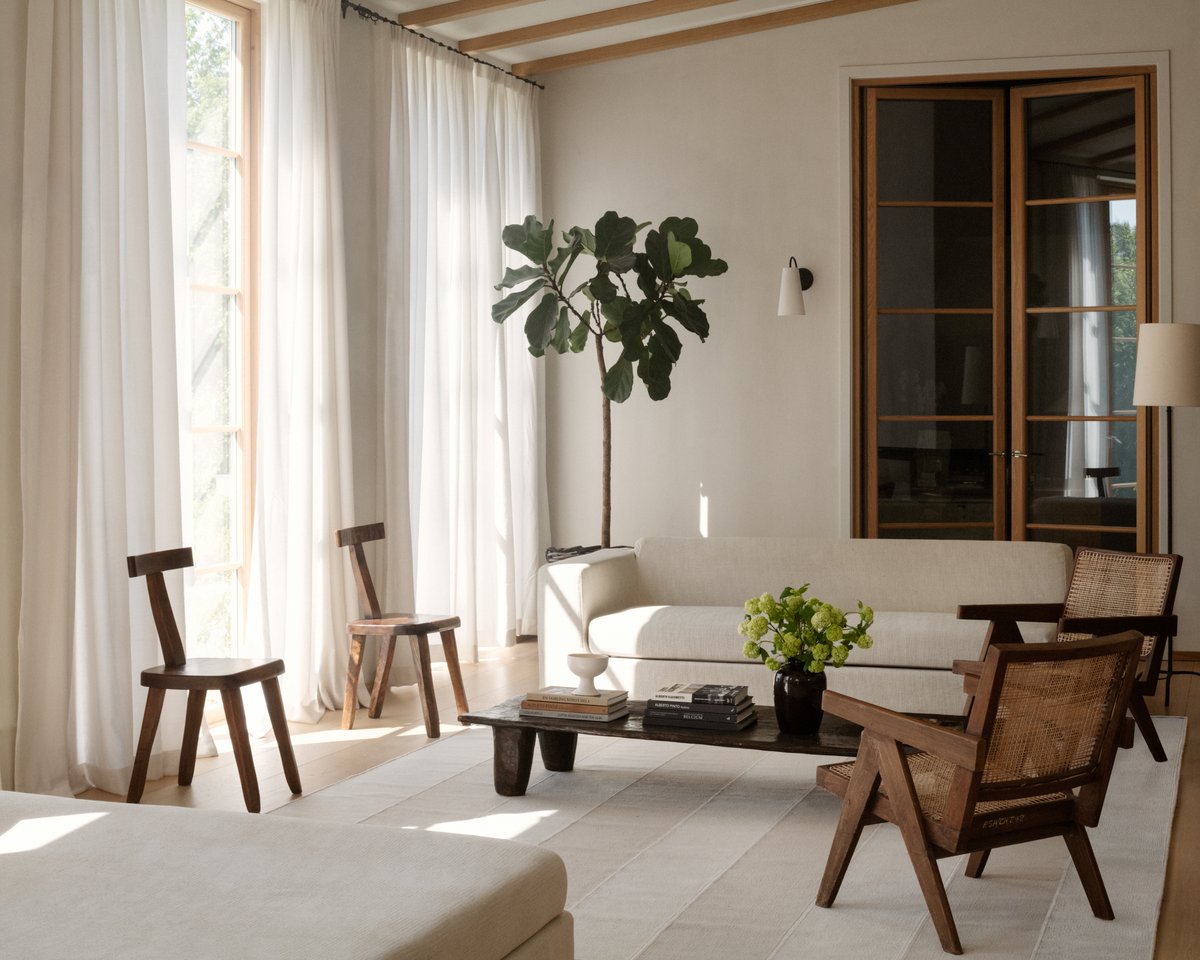 Wide Stripes Faded Nougat pictured in a living room with a white couch, wooden chairs, white curtains, and a potted tree plant.