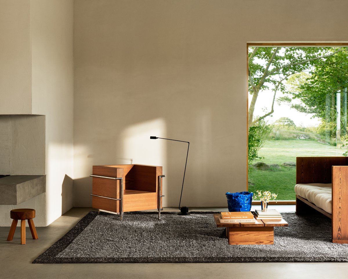 Shaggy wool rug Ryya in Black pictured in a living room with tall ceilings, wooden furniture and tall windows.