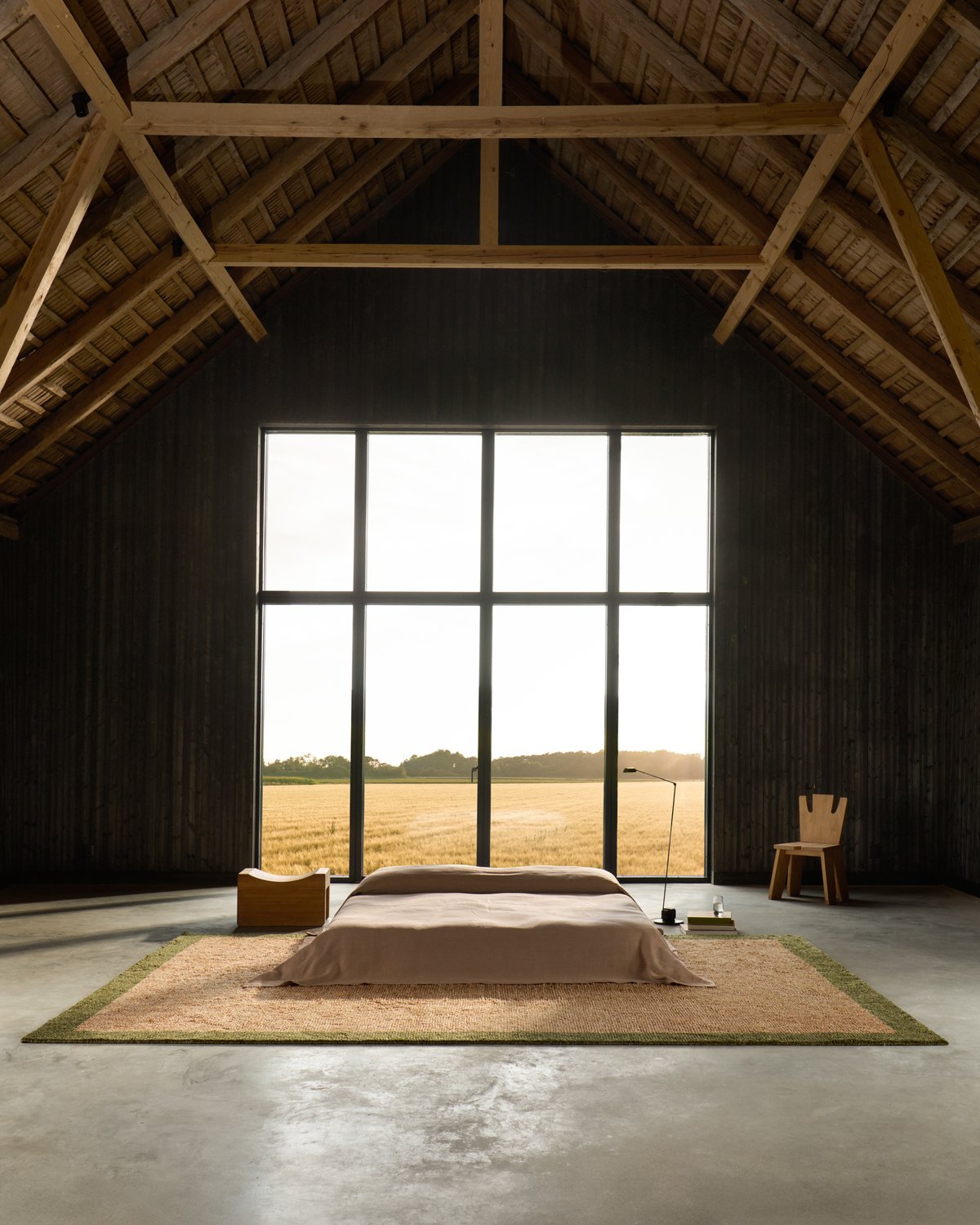 Ryya-Teppich in Beige, gespiegelt in einem großen, offenen Raum in einer renovierten Scheune mit großen Fenstern mit Blick auf ein Feld.