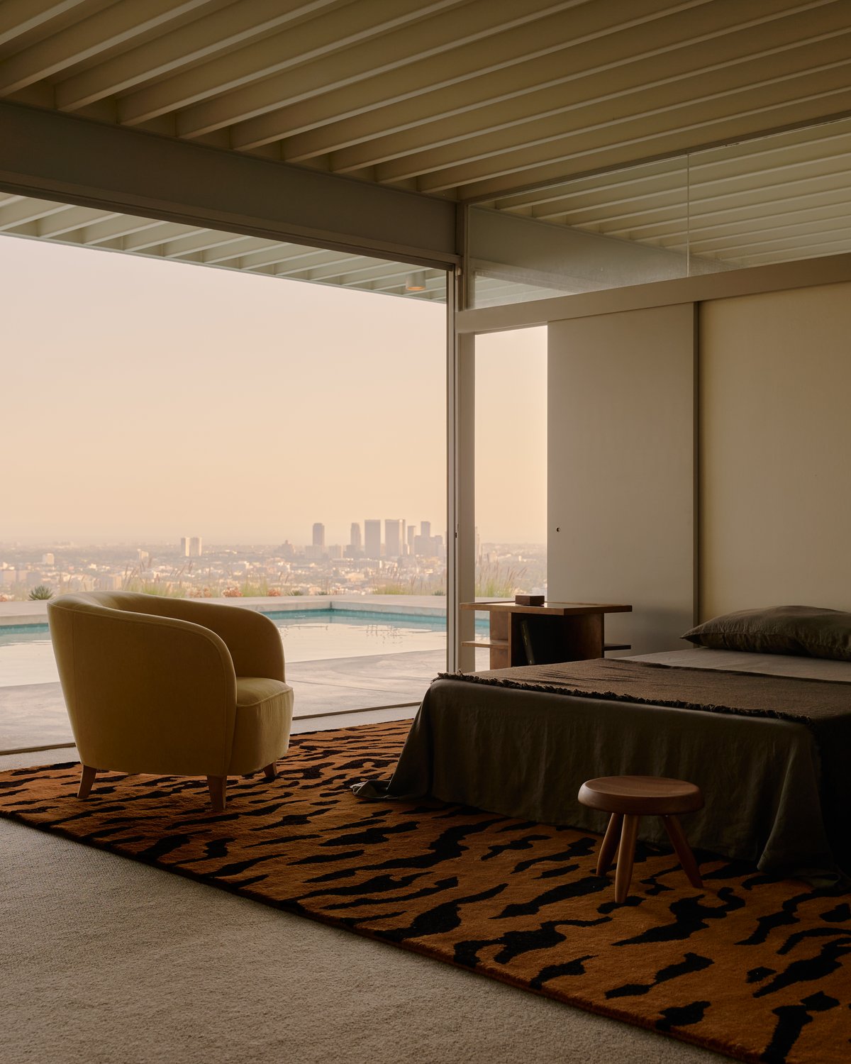 Plush wool rug Tigris in Rust/Black pictured in a beautiful bedroom with large floor to ceiling glass doors overlooking a pool and Los Angeles.