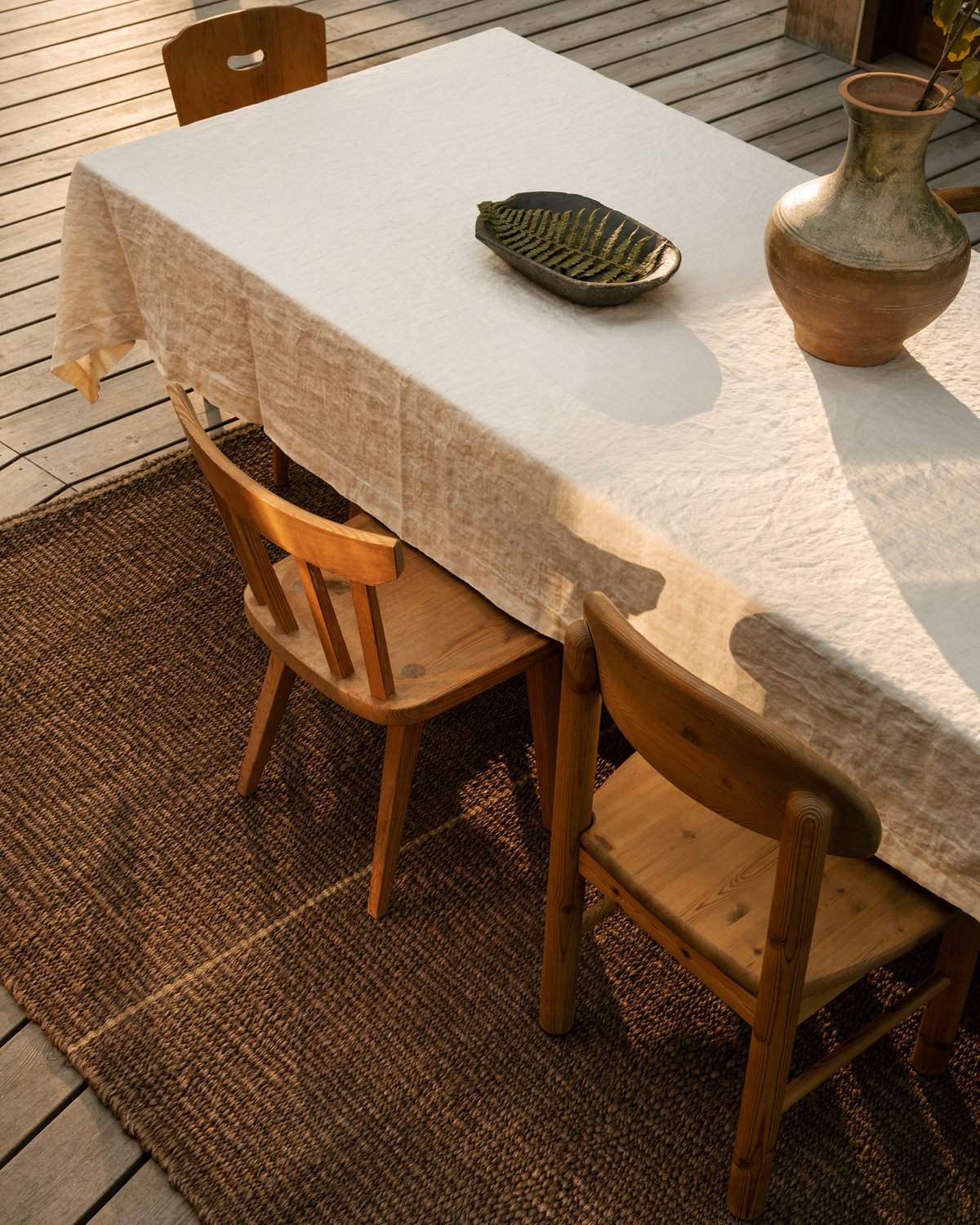 Woven abaca rug Acre displayed in a dining setting outdoors.