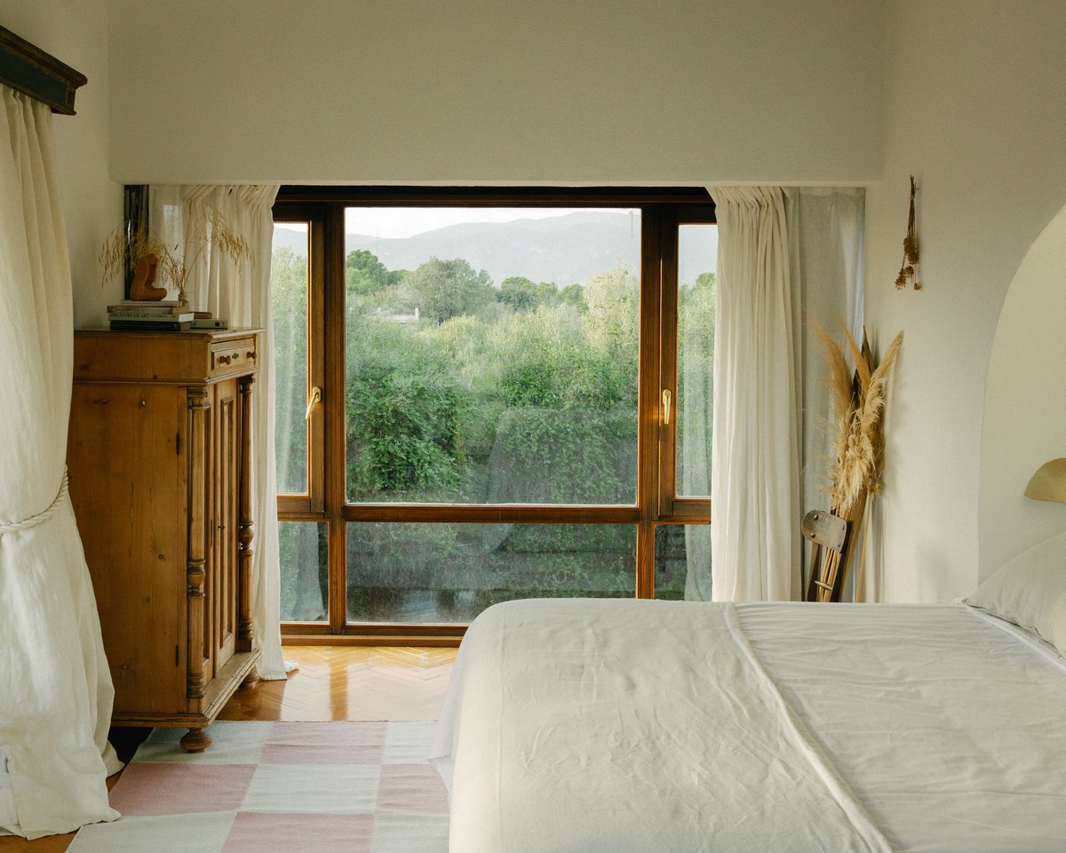 Square – Pink brings soft geometry and gentle color to this tranquil bedroom. Set against natural wood, flowing curtains, and a lush garden view, the checkered rug adds a quiet touch of playfulness and warmth.