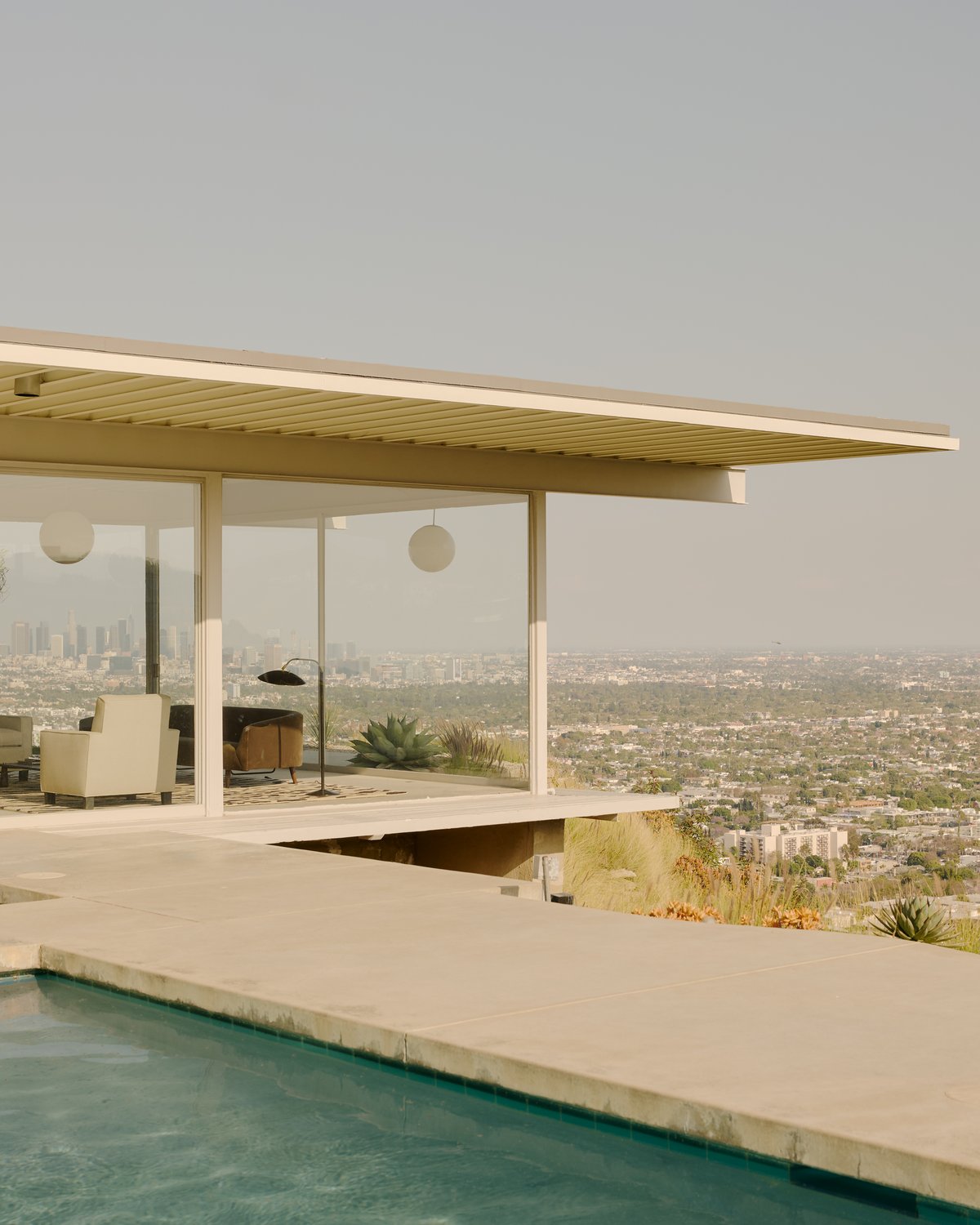 Modernes Haus mit raumhohen Fenstern und Blick auf Los Angeles in der Ferne, mit dem flauschigen Wollteppich Tigris in Beige/Brown im Wohnzimmer mit Blick auf den Pool.