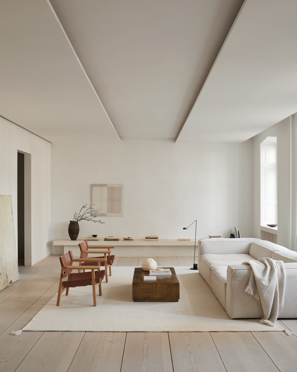 Flatweave rug Merino pictured in a brightly lit living room with wooden chairs and a soft, white couch in Copenhagen.