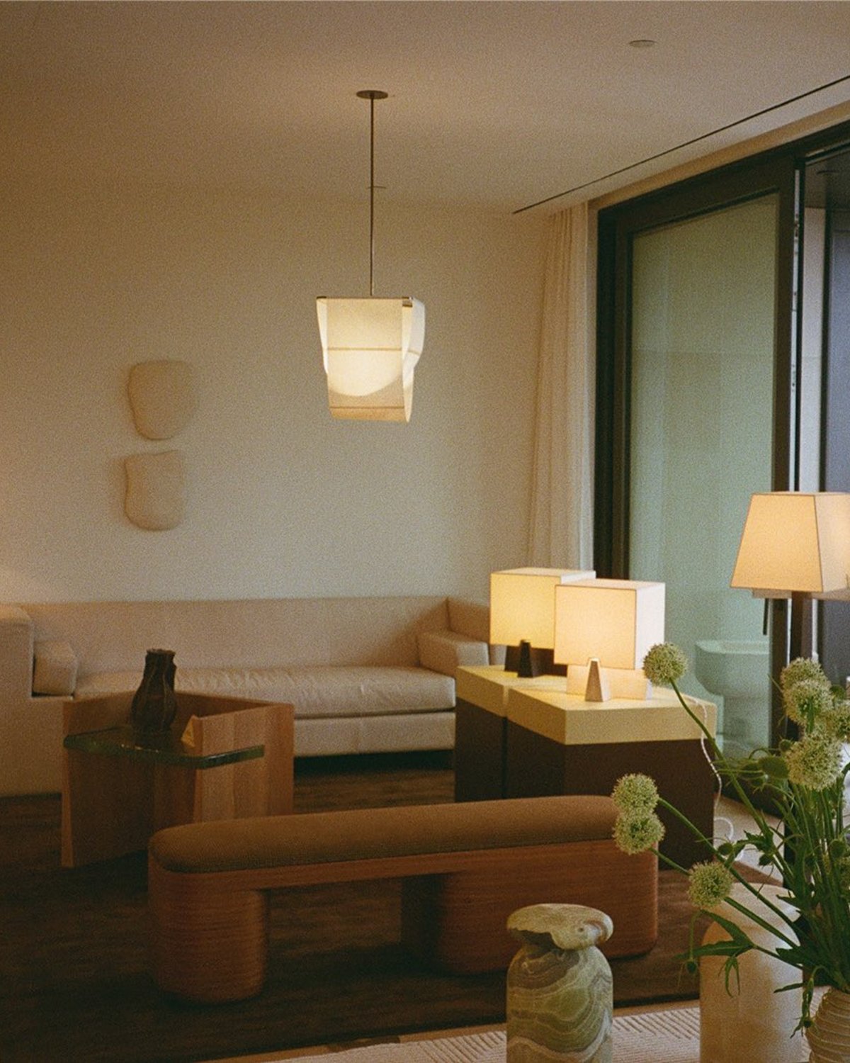 Flauschiger Wollteppich Grand Walnut, abgebildet in einem modernen Wohnzimmer mit japanisch inspirierten Möbeln, einem großen beigen Sofa und einer hohen Glastür.