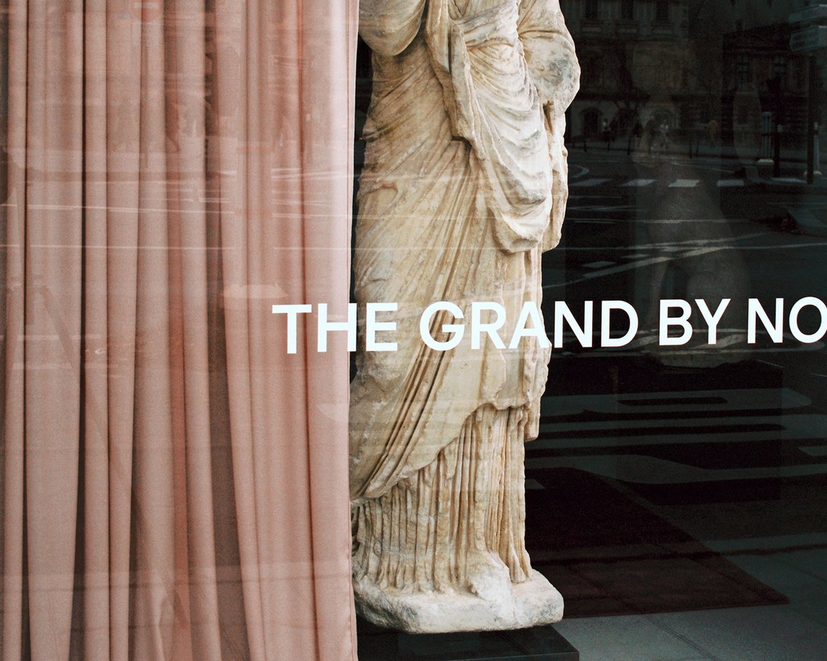 The Grand curtain in Old Rose draped near a marble statue with a window view at Galerie Chenel in Paris.
