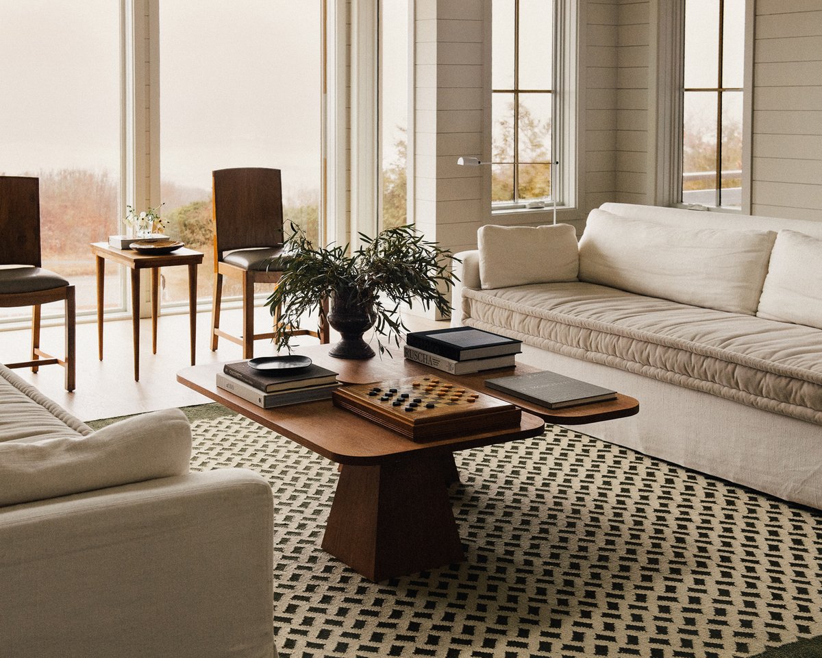 Orleans rug in Beige/Green as the centre of attention in a light living room, paired with two cream sofas and a wooden coffee table.