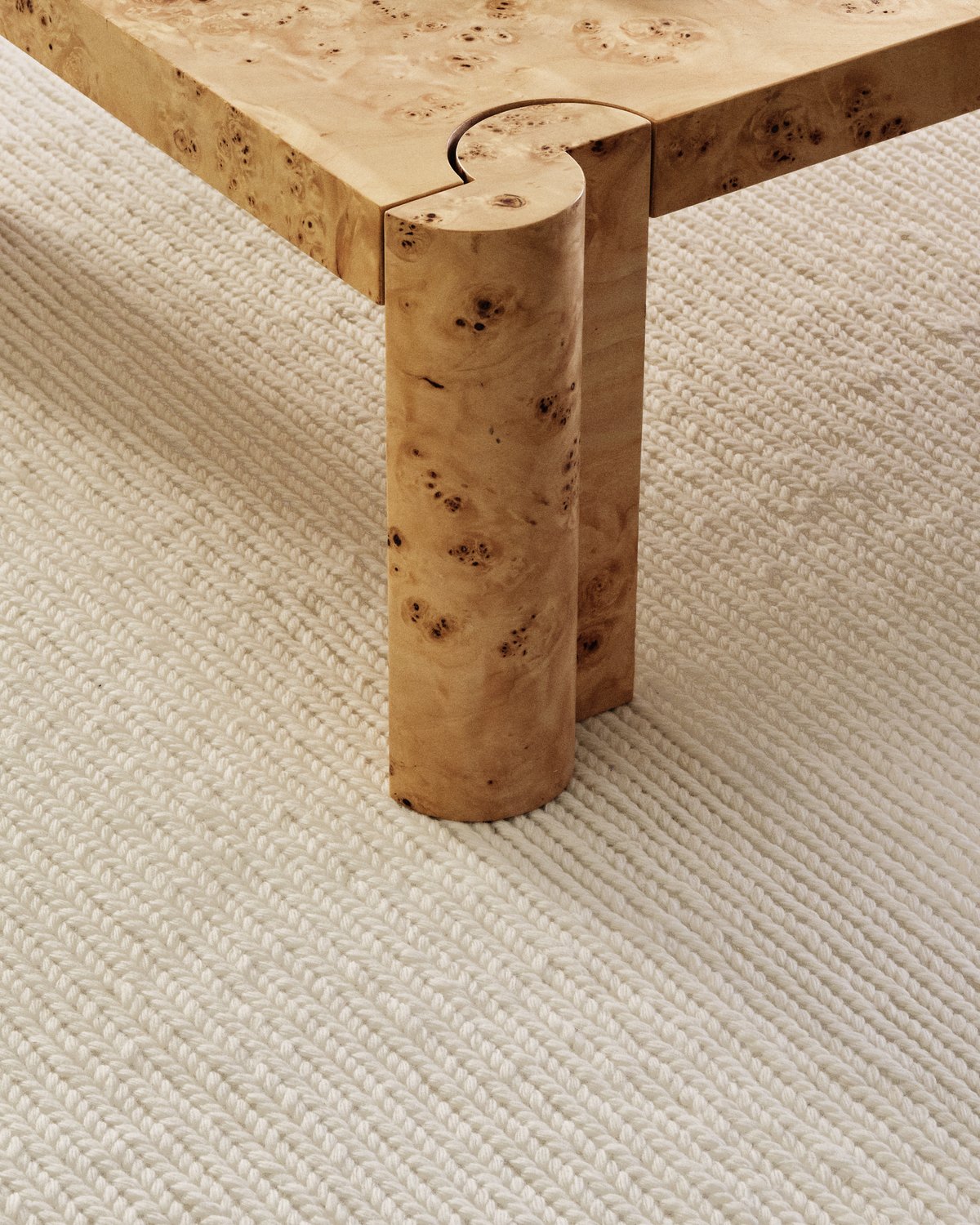 Nahaufnahme des flachgewebten Wollteppichs Braid in der Farbe Cream unter einem Couchtisch aus Holz.