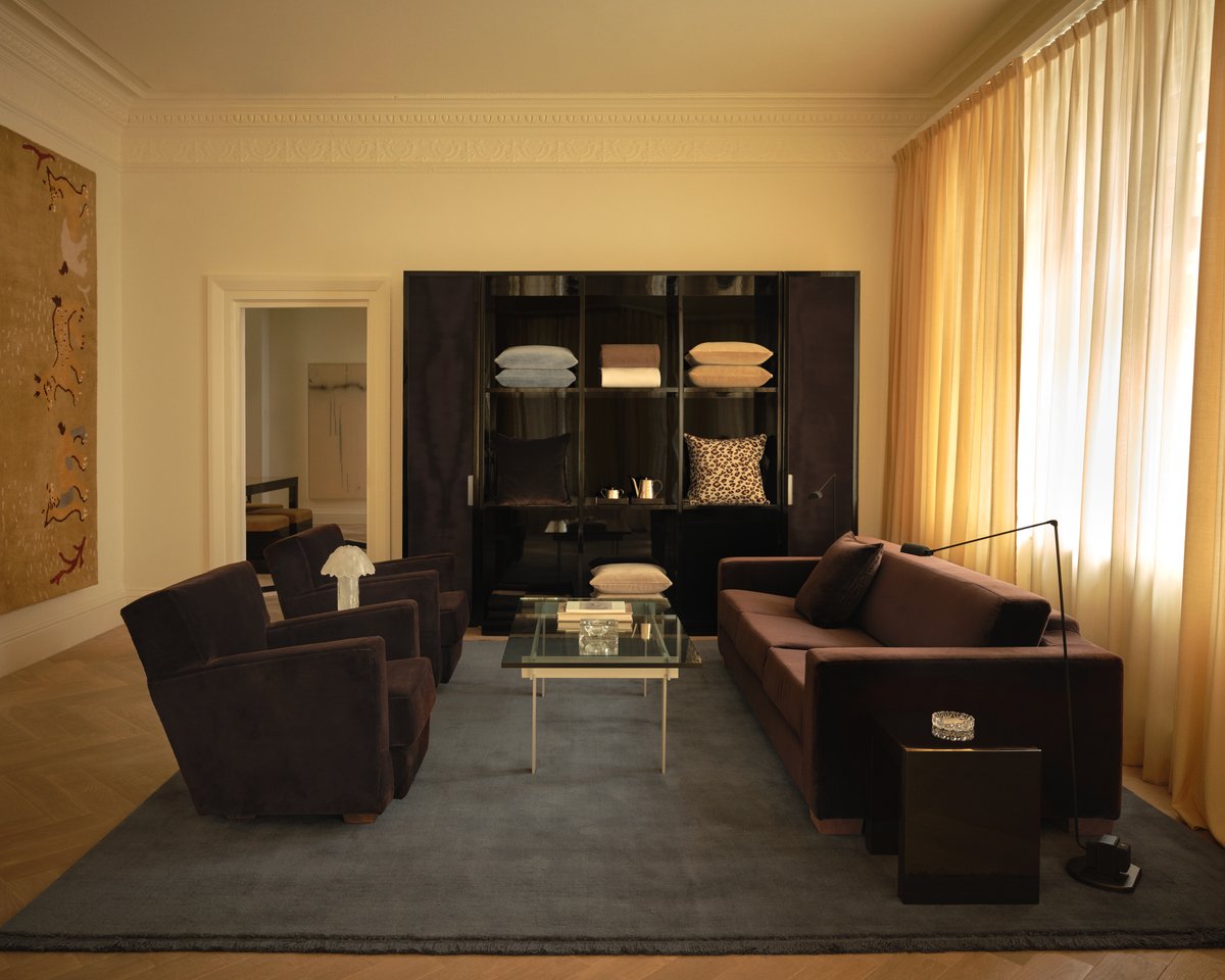 The Mohair rug in Slate Blue is shown in the Nordic Knots store on Mount Street in London, styled with dark velvet furniture, The curtains in Leo, and a glass coffee table, creating a refined and contemporary atmosphere.