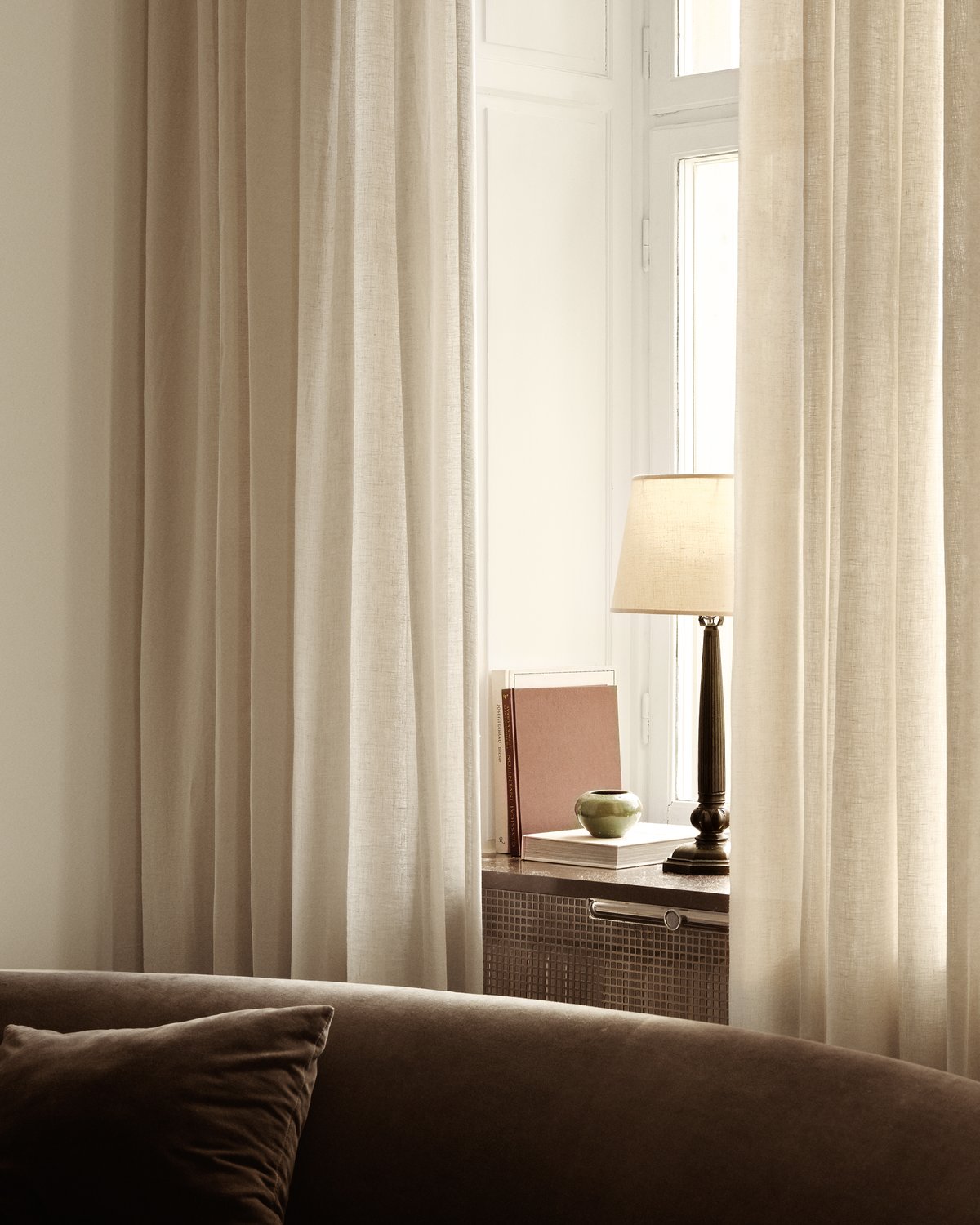 The Sheer Linen curtains in Almond in a bright living room, framing a window with neutral toned accessories.