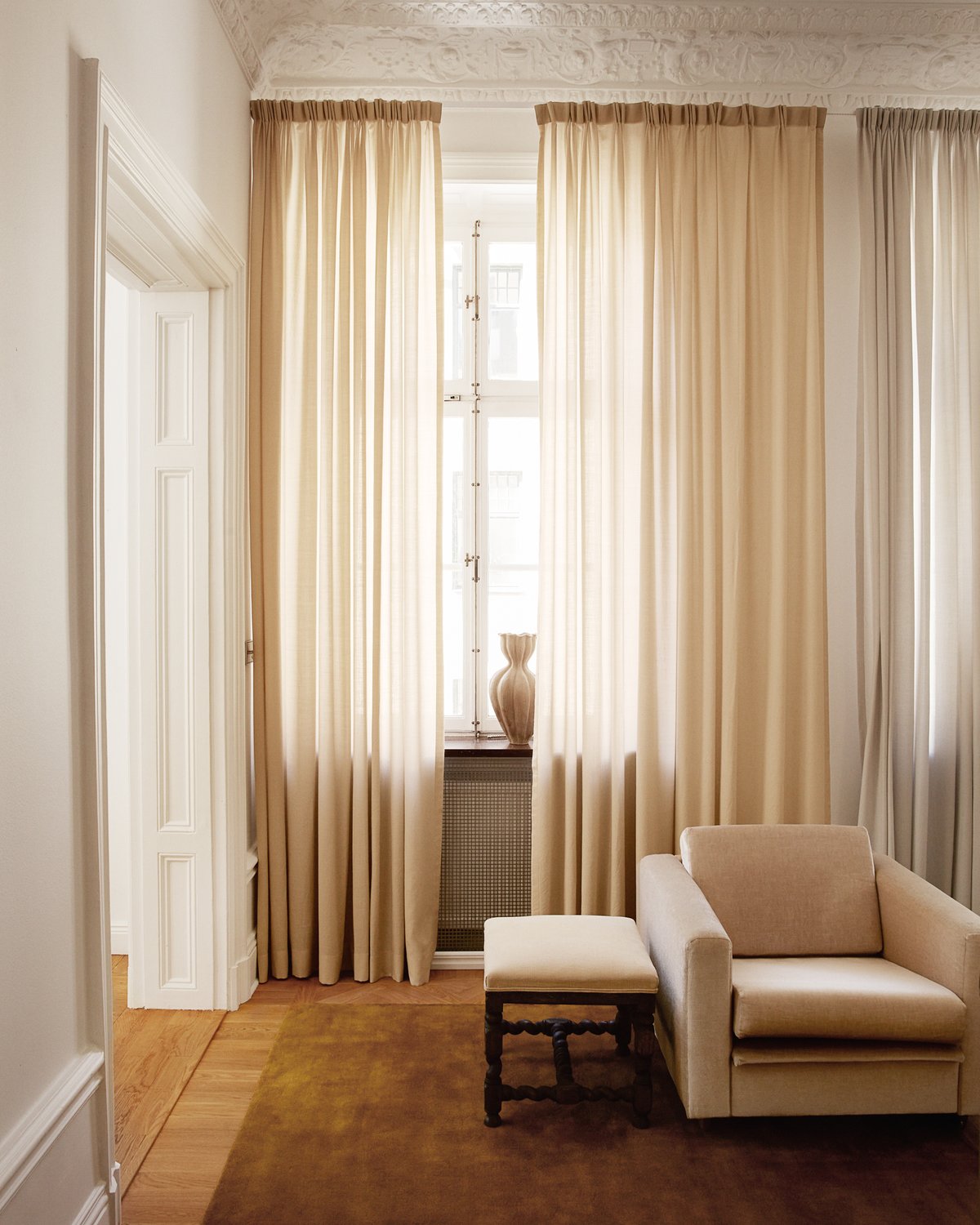 Wool curtain The Grand in Pale Sand displayed in large windows in a home with soft and muted colours.