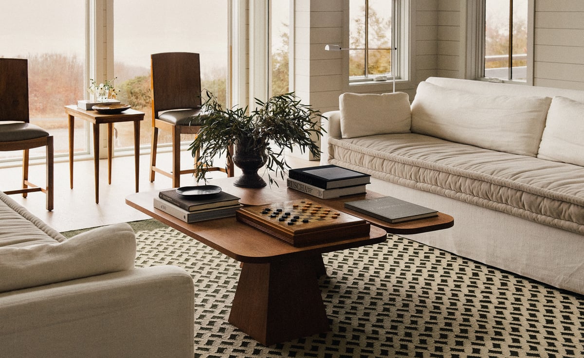 Orleans – Beige/Green brings quiet pattern and grounded elegance to this light-filled space. The geometric weave complements clean-lined cream sofas and a sculptural wooden coffee table, creating balance between softness and structure in a room framed by natural light and warm, minimal details.