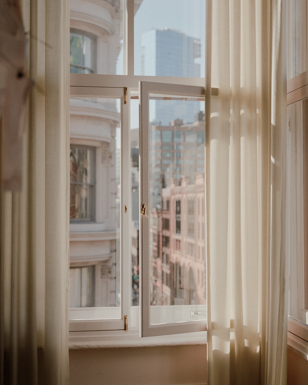 Photo d'une fenêtre ouverte avec les rideaux en laine The Grand tirés sur les côtés.