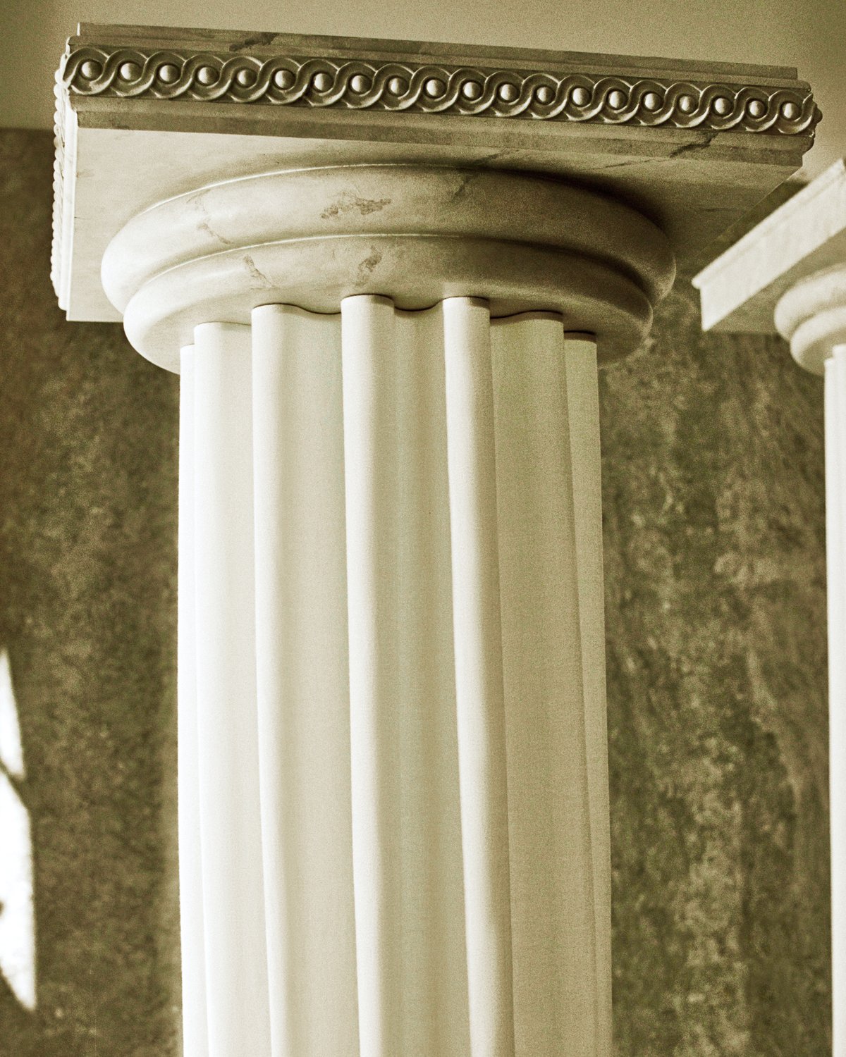 The Grand curtains on an ancient greek style pillar in the Stockholm Flagship with the light shining in through the windows onto the green marble interior.