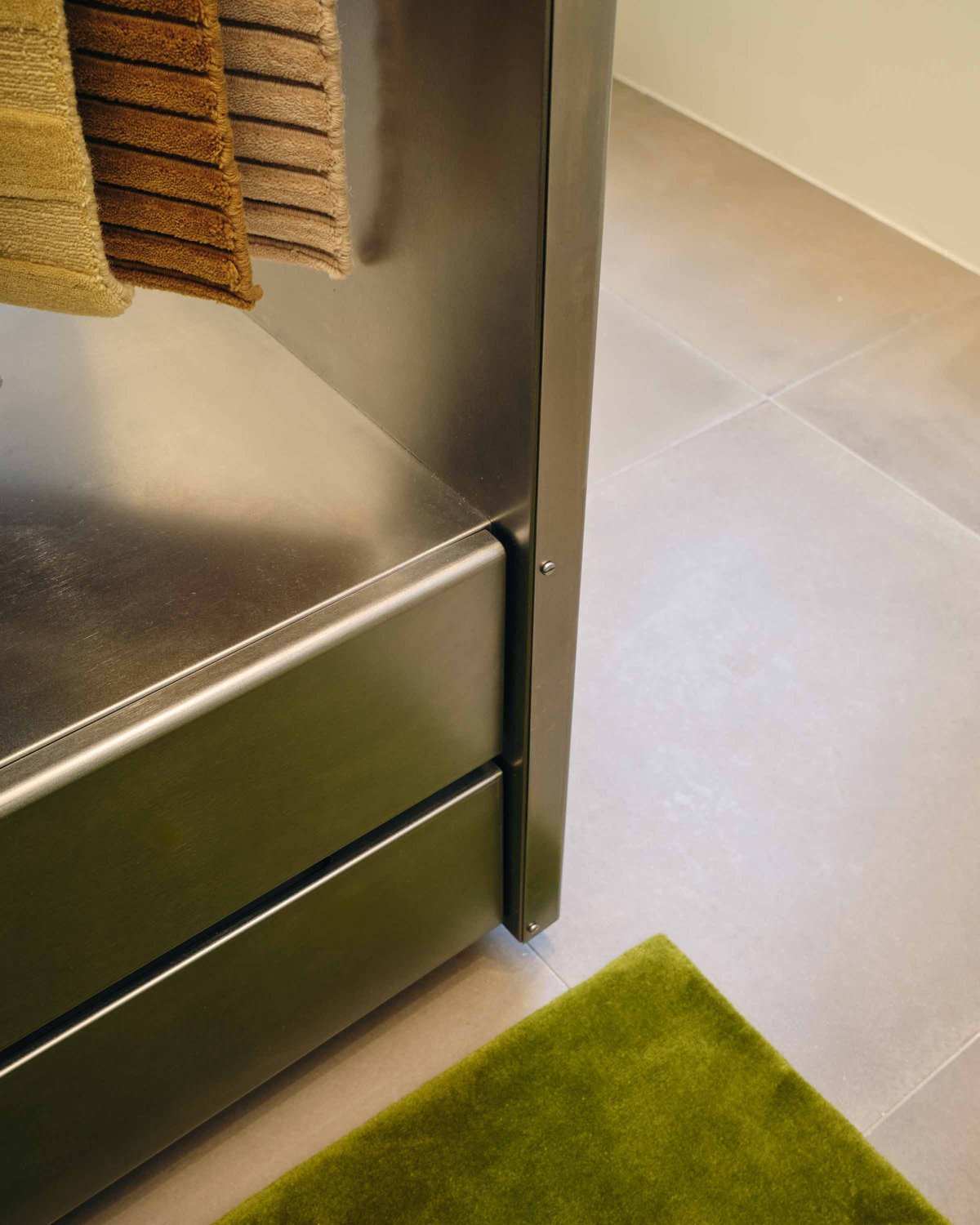 Nahaufnahme des flauschigen Wollteppichs Grand Milano Green und der Metallständer für die Teppichmuster.