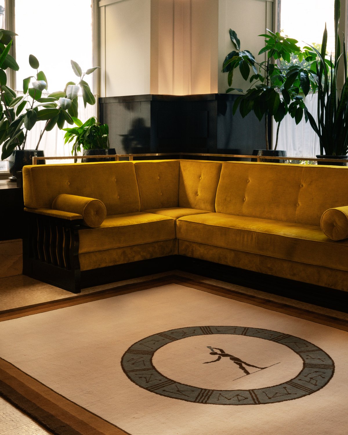 Plush wool rug designed by Parisian designer Fabrizio Casiraghi next to a soft yellow velvet sofa and plants next to large windows in Paris, France.