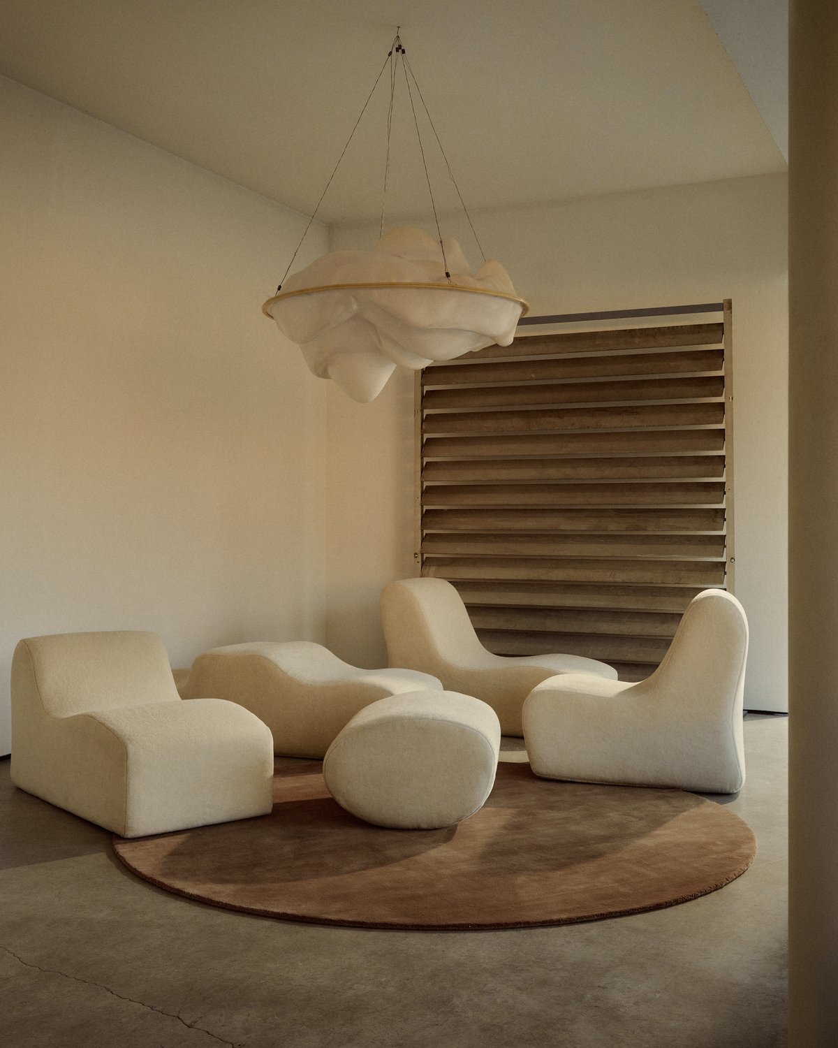 Mattan Grand Round i färgen Chestnut, placerad under flera skulpturala krämfärgade fåtöljer.